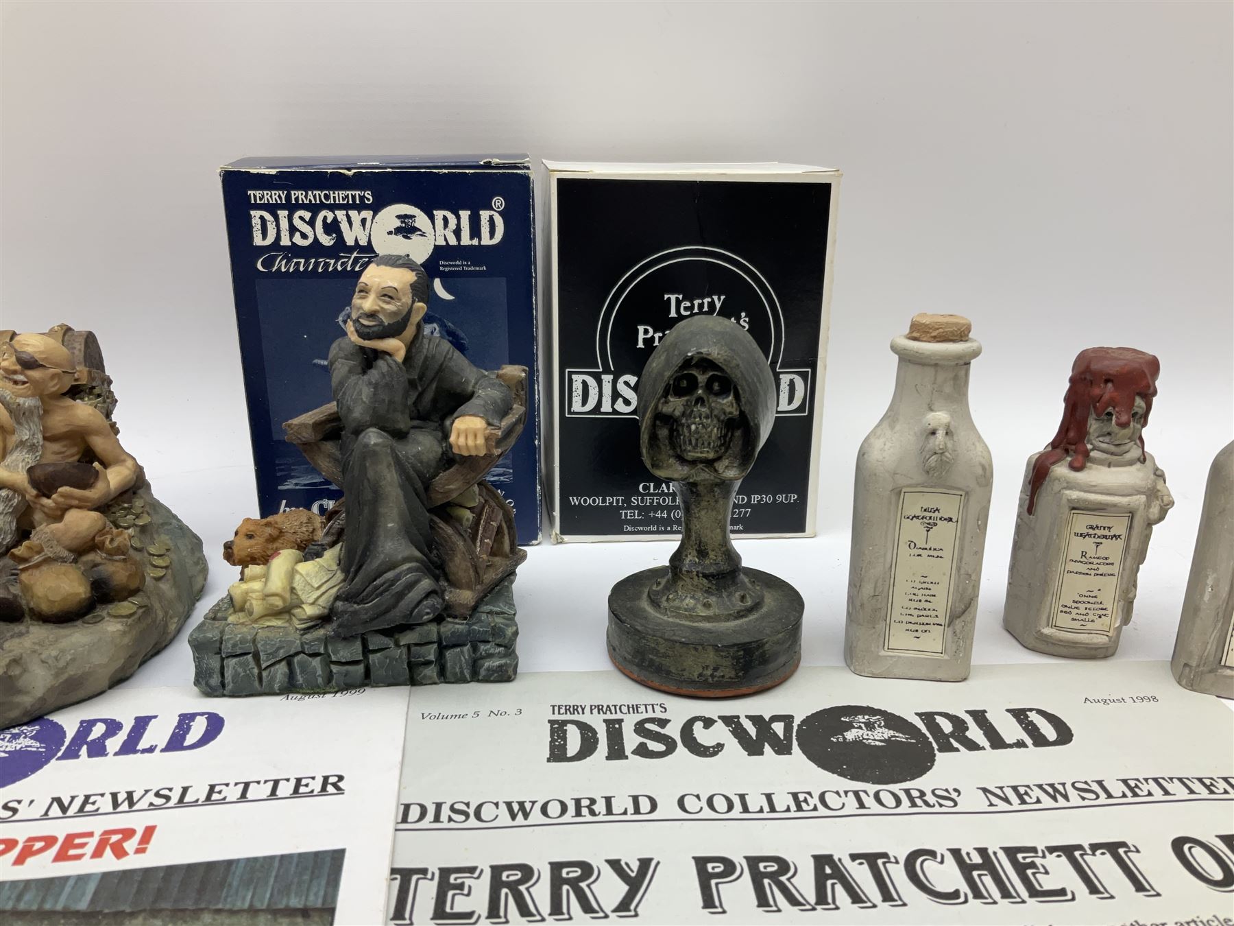 Terry Pratchett Discworld figures, designed by Clarecraft, comprising Cohen the barbarian, DW42, the Patrician, boxed, DW37, three Potions, DW18, DW19, DW20, two Death Bookstamps, DW50, the Gods Dice Box, boxed, DW26, together with two Discworld newsletters, volume 5, August 1998 and volume 6, August 1999. 