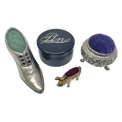 Three pin cushions, comprising gilt metal pig, silver plate shoe, circular pin cushion on threel feet, together with black pin holder with silver writing to the lid 