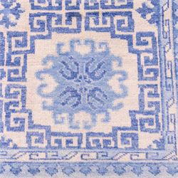 Late 20th century Chinese hand-woven wool carpet, ivory field with a lattice of stylized lotus medallions, contained within geometric key fret panels interspersed with a small floral device enclosed within a complementary Greek-Key border, the designs in tones of pale blue and soft cream