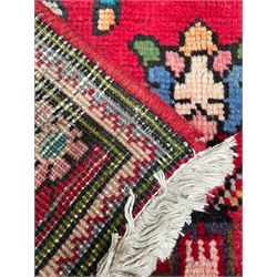 Persian Azerbaijan crimson ground rug, the field decorated with central floral motif and surrounded by trailing floral branches, enclosed within a shaped outer band with further floral decoration, the border with repeating flower heads, geometric guard stripes 