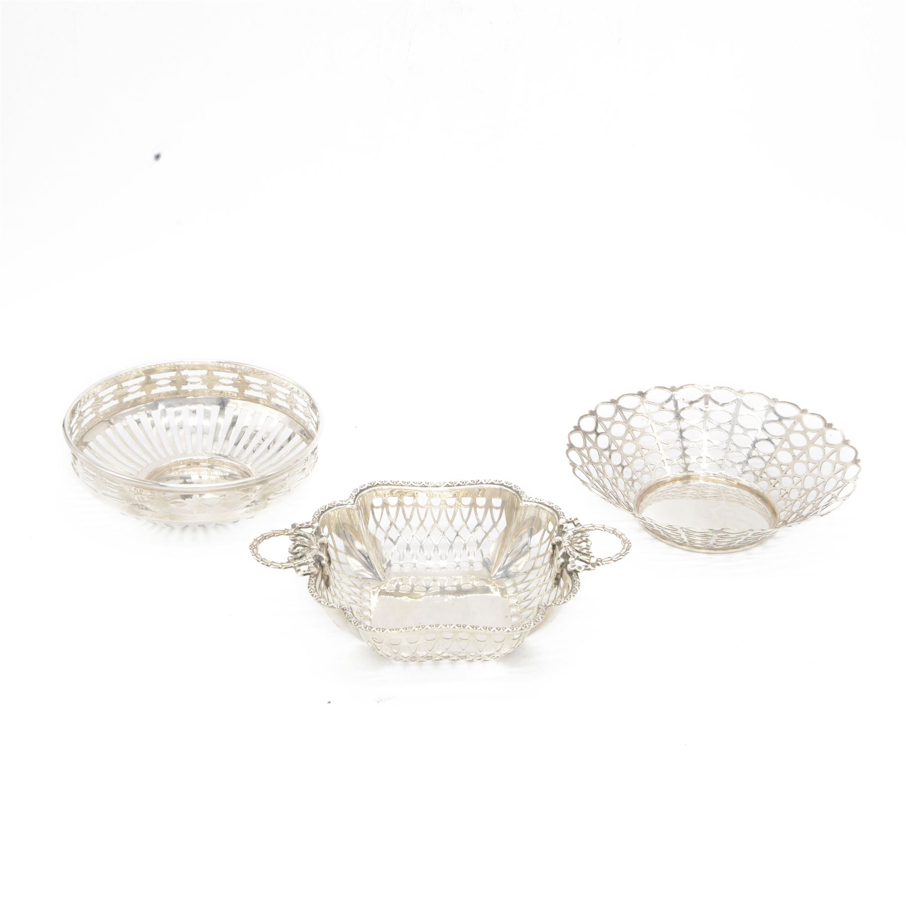 Three mid 20th century silver bowls, including two circular examples with pierced sides and a square example with twin handles, all hallmarked