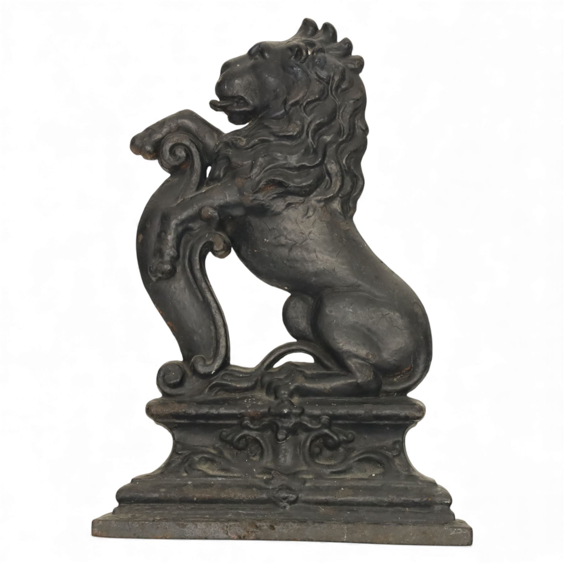 Victorian cast iron figural doorstop in the form of a lion, depicted seated with curled tail and detailed mane, raised foreleg resting against a scroll motif, set on an integral stepped base with moulded edges and foliate ornament