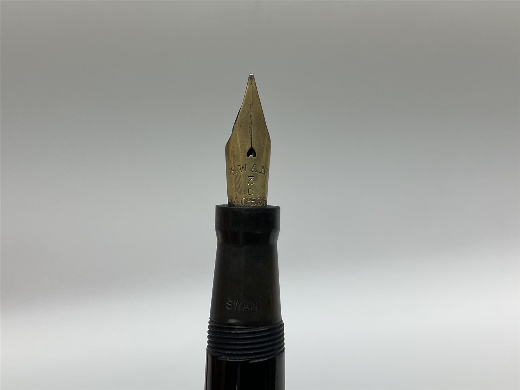 Vintage Swan Mabie Todd lever fill fountain pen in coral red, the nib a/f marked 14K, together with two further vintage Swan Mabie Todd fountain pens, the first example with lever fill, the other leverless, each with black body, one with nib marked 14ct, (3) 