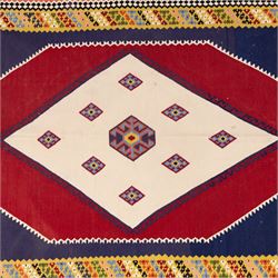 South West Persian Qashqai kilim, woven in flatweave with tones of indigo blue, madder red, yellow, turquoise, and green, with a bold central diamond medallion on an ivory ground, enclosing smaller lozenge motifs and flanked by deep madder red panels, field framed by a broad indigo border with polychrome geometric devices and serrated motifs 