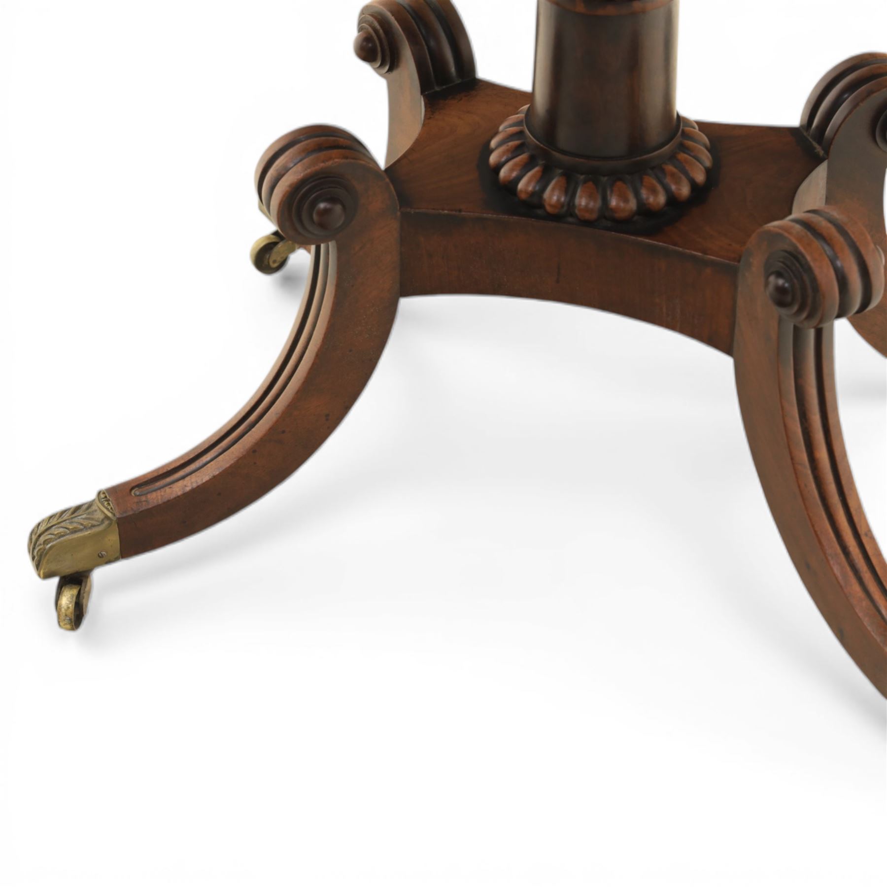 Early 19th century Regency mahogany fold over card table, the rounded rectangular top with brass line inlay enclosing green baize playing surface, crossbanded and strung exterior, with reeded edge above a gadrooned frieze, raised upon a turned column and four reeded sabre supports terminating in brass caps and castors