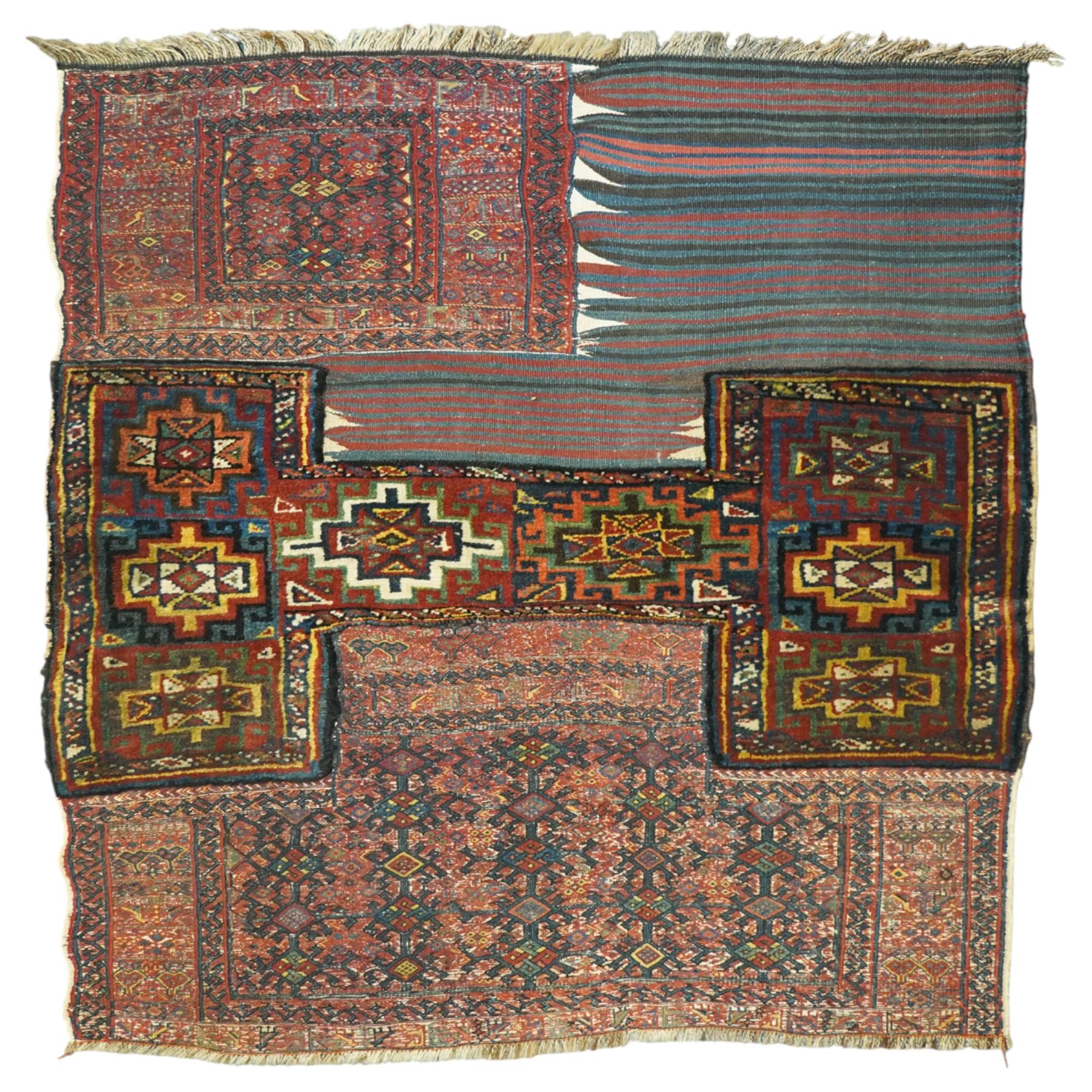 Central Asian vintage saddle cover, probably Turkmen, wool pile and flatweave on wool foundation, decorated with geometric tribal motifs in a palette of madder red, indigo, ivory, and dark brown, with cotton fringe ends 