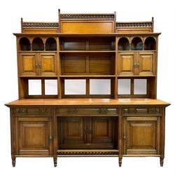 Late Victorian walnut dresser, the raised panelled back fitted with panelled cupboards, shelves and bevelled mirrors, moulded rectangular top over three drawers and cupboards, the left-hand cupboard fitted with two slides and the right-hand cupboard fitted with revolving drinks stand, on turned feet