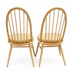 Ercol - light elm set of four Quaker style chairs, high arched backrest with slender spindles, solid wood seat with elasticated strap cushion, on round tapered out swept legs (4)