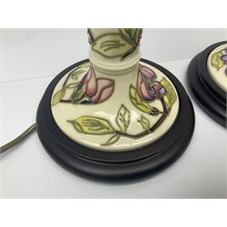 Pair of Moorcroft table lamps of candlestick form in magnolia pattern, with Moorcroft shades, H50cm 

