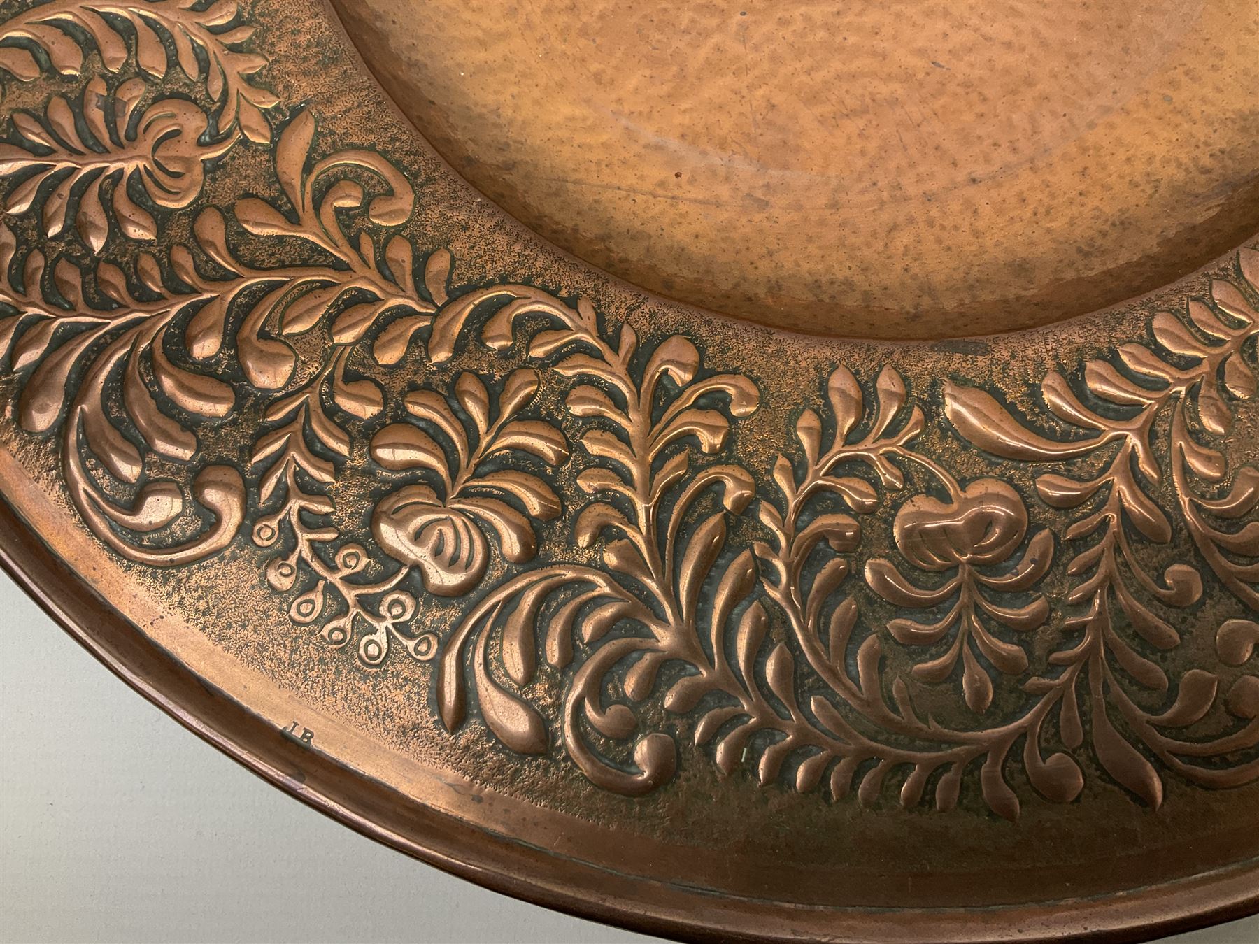 Arts and Crafts Keswick School of Industrial Arts copper charger, decorated with planished centre and repousse scrolling foliate tendrils to rim, D44cm