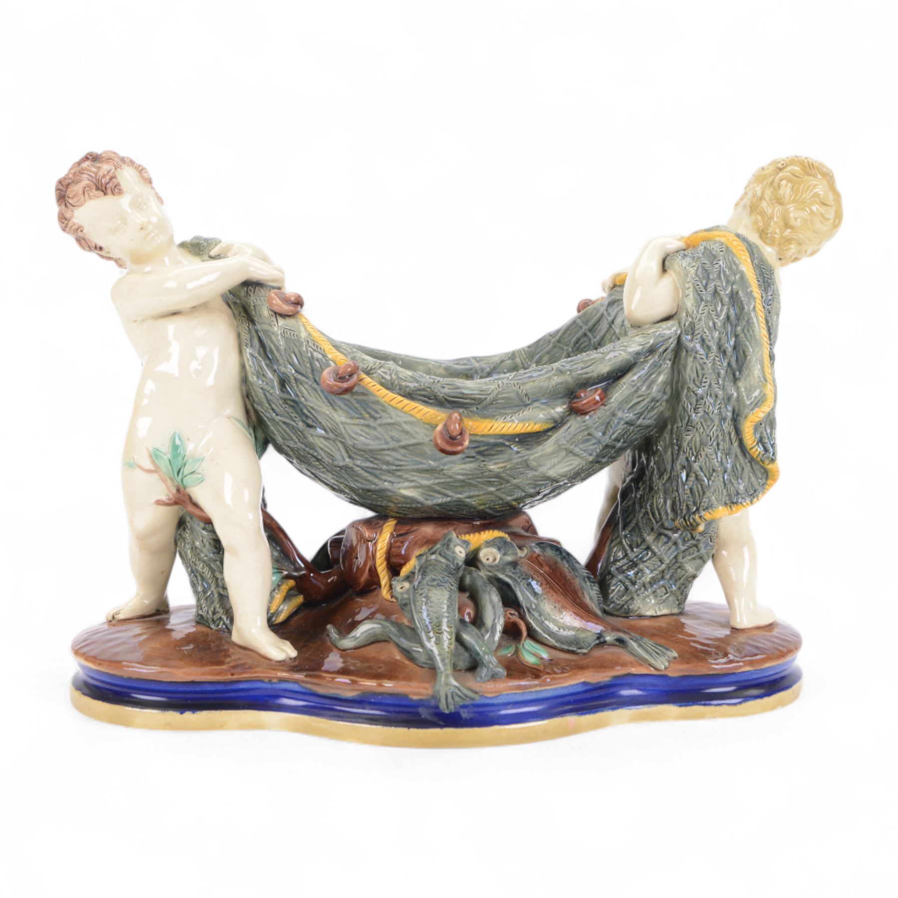 Late 19th century Copeland majolica centrepiece, circa 1874, modelled as two putto standing with fishing net draped between them, their catch spilling onto the quatrelobed base beneath, with impressed mark beneath, H24cm W33cm 