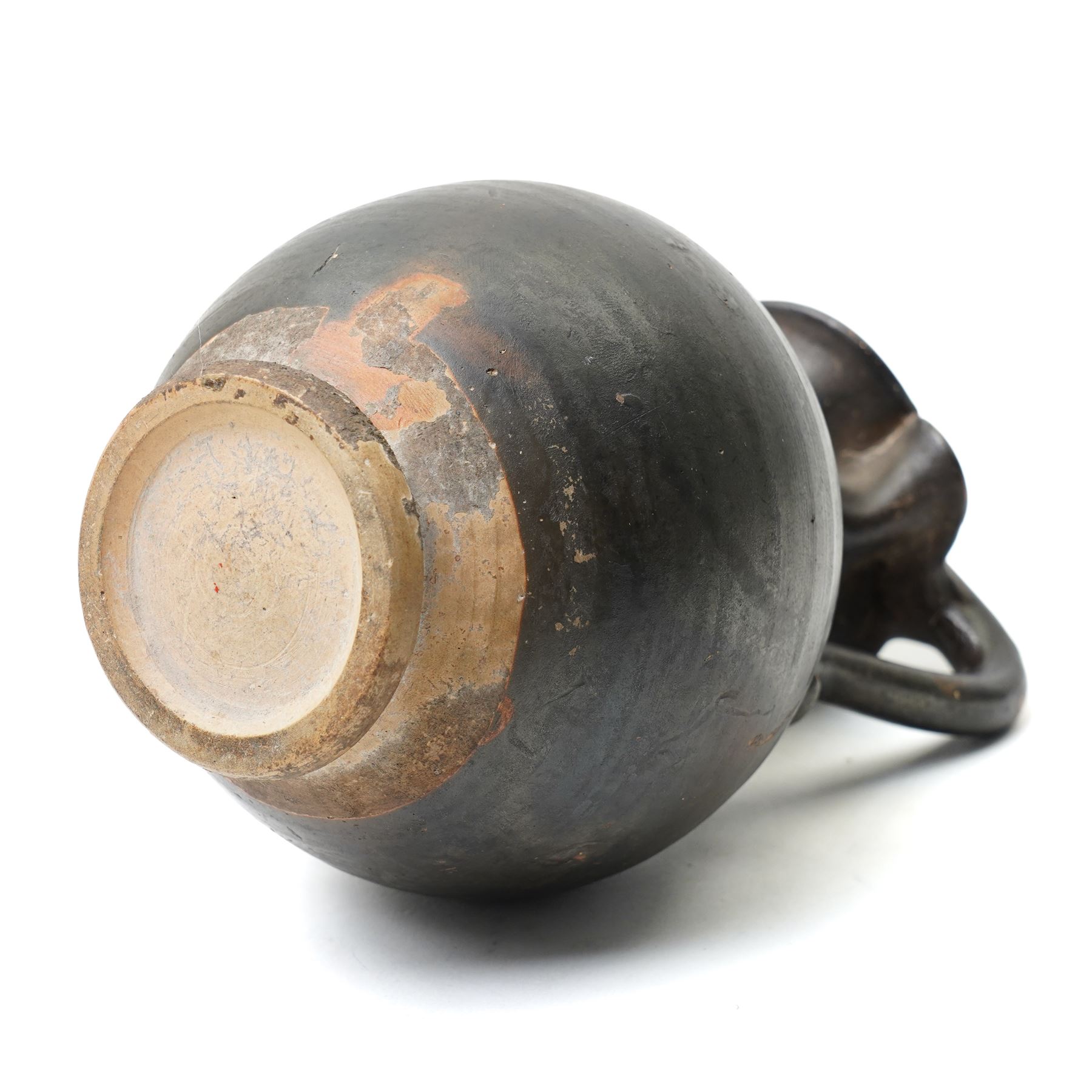 South Italian Gnathian terracotta oinochoe (jug) Apulian or Campanian (Late 4th century BC c.325-300 BC) of elegant ovoid form with trefoil mouth and single strap handle, the handle terminating in a stylised serpentine motif merging into the pouring lip, the vessel covered in a black gloss slip and decorated in added red, white and yellow with a theatrical mask, fillets and scrolling Dionysiac vine motifs, H19cm 
Notes: Gnathian ware takes its name from Egnathia in Apulia and is characterised by a black-gloss ground with added-colour decoration; the theatrical mask, fillets and vine scrolls relate to Dionysiac imagery associated with the symposium and theatre in South Italian Greek culture of the late fourth century BC. A very similar oinochoe is held in the The Metropolitan Museum of Art, object number 76.12.8