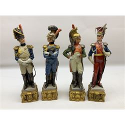 Group of seven Capodimonte figures of soldiers, to include four Bruno-Merli examples including Officer of the 12th Lancers 1820 and Captain of the 18th Hussars 1815, both raised upon ornate gilt plinths bearing British monarch motto in Latin 'Dieu et mon droit', and three further similar, all with crowned N mark beneath, tallest H32cm