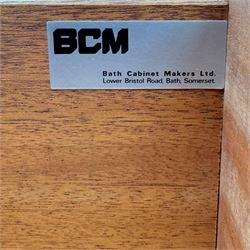 BCM (Bath Cabinet Makers) - mid-20th century teak sideboard, rectangular top with back gallery, left hand side fall front cupboard, centre cupboard opening to reveal a shelved interior, the right side with a bank of three drawers one fitted for cutlery, raised on inset tapering supports