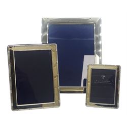 Modern silver mounted photograph frame, of plain rectangular form with navy plush lined back and easel style support, hallmarked Carr's of Sheffield Ltd, Sheffield 1983, overall 22cm x 17cm, aperture 18cm x 13cm, together with two smaller silver mounted photograph frames, each of rectangular form with ribbon wrapped reeded border, the largest example hallmarked Kitney & Co, London 1999, overall 15.5 x 11.5cm, aperture 12.5cm 9cm, the smaller hallmarked London 1996, makers mark worn and indistinct, overall 10.5cm x 8cm, aperture 8cm x 5.5cm, (3)