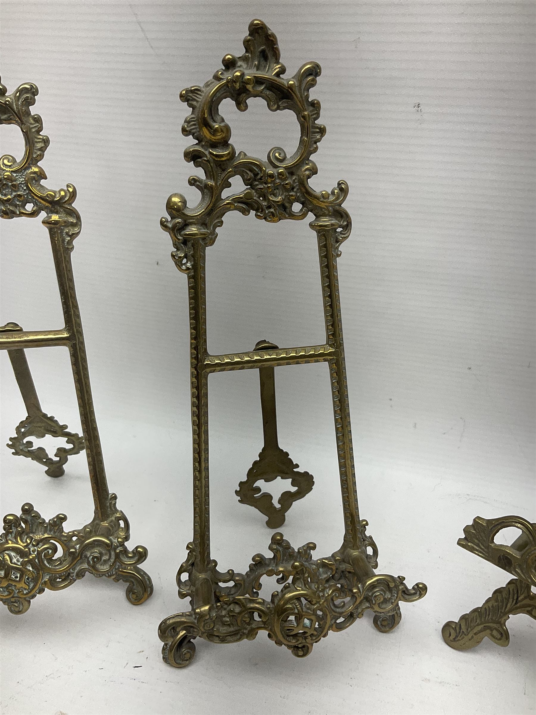 Nine ornate cast brass easel stands of various sizes, H24cm