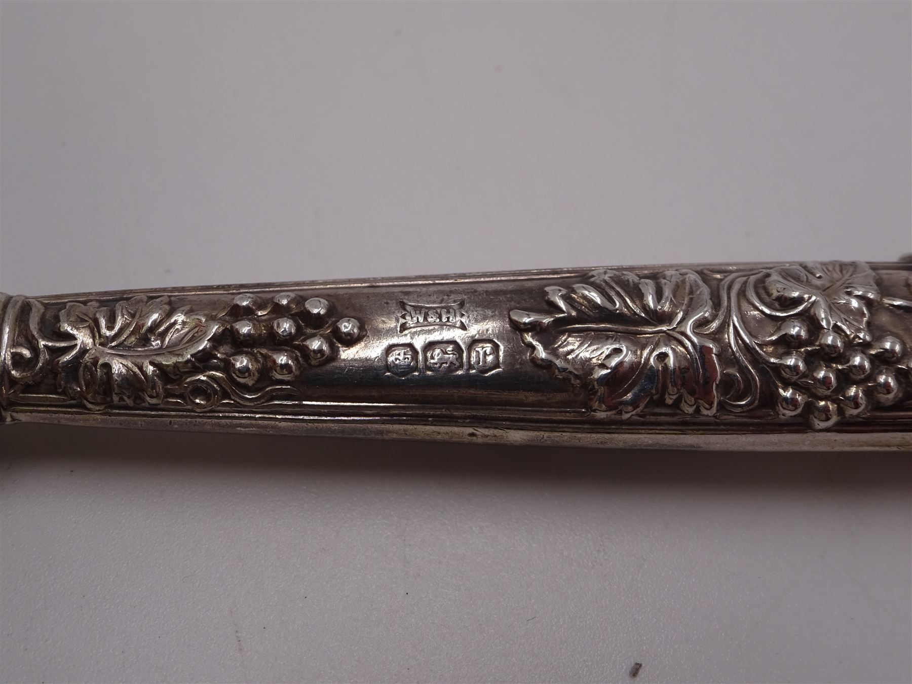 Set of 1930s silver handled fruit knives and forks, for six place settings, the handles decorated in relief with fruiting vines, hallmarked Walker & Hall, Sheffield 1934, together with a set of six 1920s silver egg spoons, with pin prick engraving to handle, hallmarked Thomas Bradbury & Sons Ltd, Sheffield 1929, in fitted case, three silver napkin rings, to include a pair, of octagonal form, with floral engraving, hallmarked John Rose, Birmingham 1951 and two silver souvenir spoons