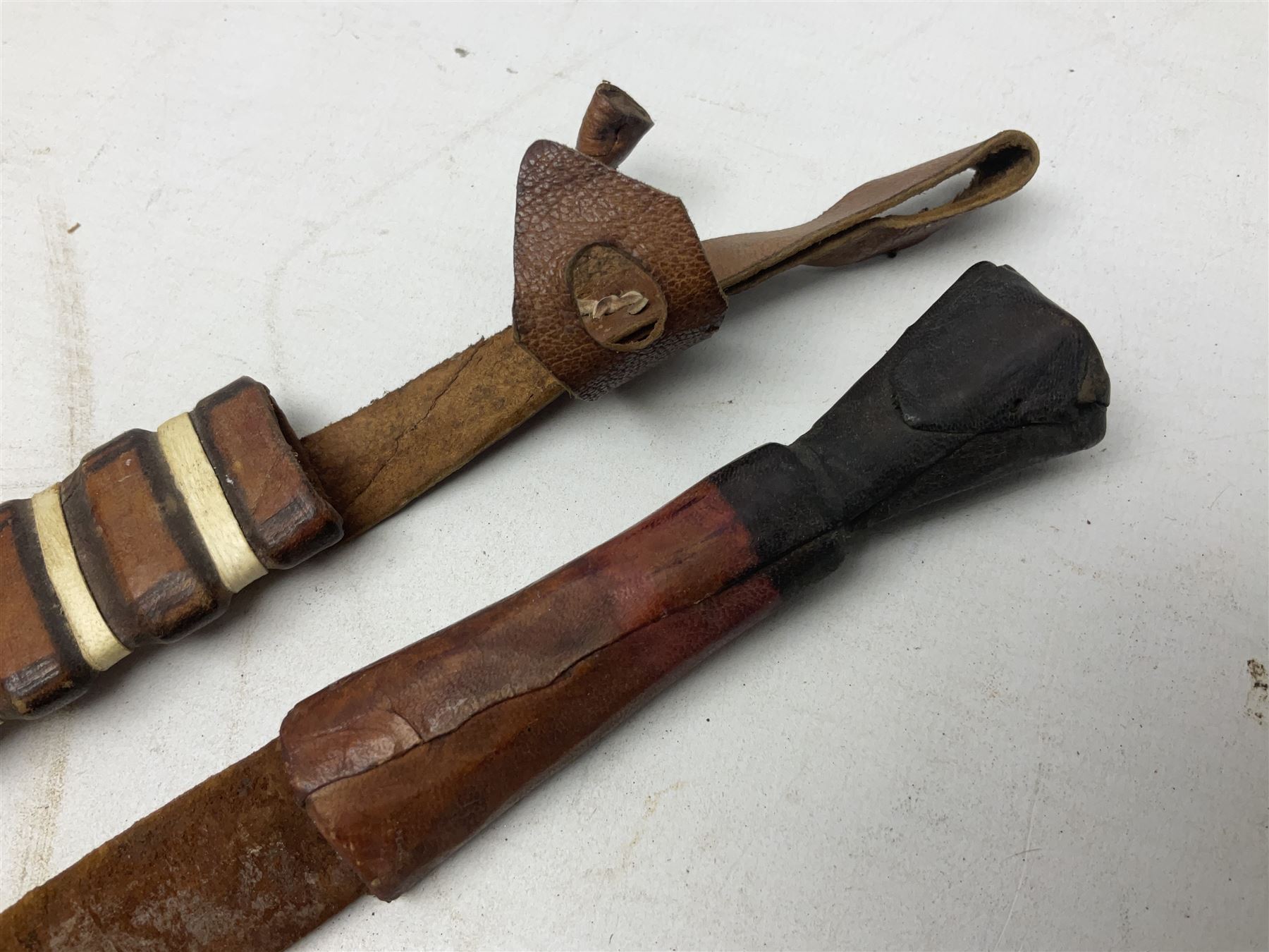 Indian kukri with 29cm curving steel blade and nickel mounted horn grip; in leather covered scabbard with one skinning knife L42cm overall; Hitler Youth knife with scabbard in relic condition; and three African graduated knives each with crudely carved wooden grips and painted leather covered scabbards (5)