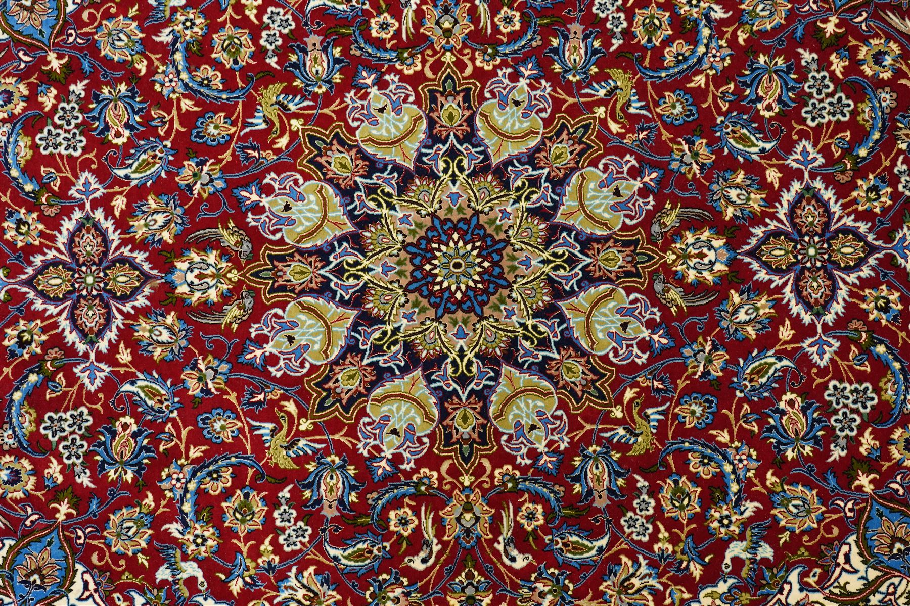 Fine Central Persian Isfahan hand-knotted rug, madder red field with central finely drawn foliate medallion issuing an intricate all-over scrolling vine design with palmettes and arabesques, enclosed by multiple conforming borders in navy ground, signed Isfahan in cartouche, silk fringe ends 