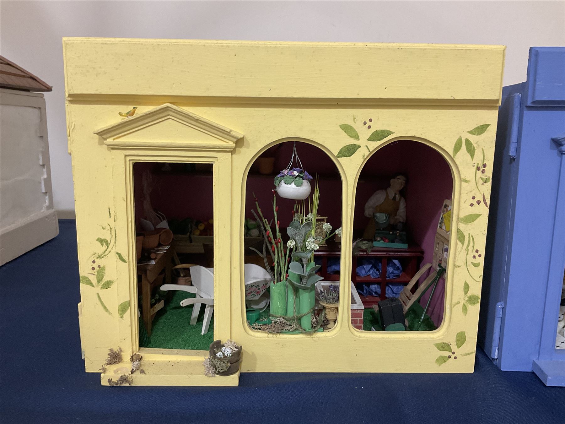 Three scratch-built wooden shop dioramas - single room Pet Shop with hinged front, fully furnished and well stocked with animals, birds and numerous accessories; and matching Garden Shop, fully furnished and well stocked with fruit, vegetables and garden accessories including lawn mower, wheelbarrows etc; each W34cm H27cm D26cm; and double fronted single room Butchers Shop with butcher at his block, partially stocked counter and two delivery cycles W57cm (3)