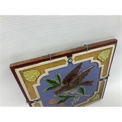 19th century Minton & Co majolica tile, decorated in relief with a bird upon a fruiting branch against a blue ground, with textured ochre border and anthemion to each corner, impressed mark verso, H19.7cm
