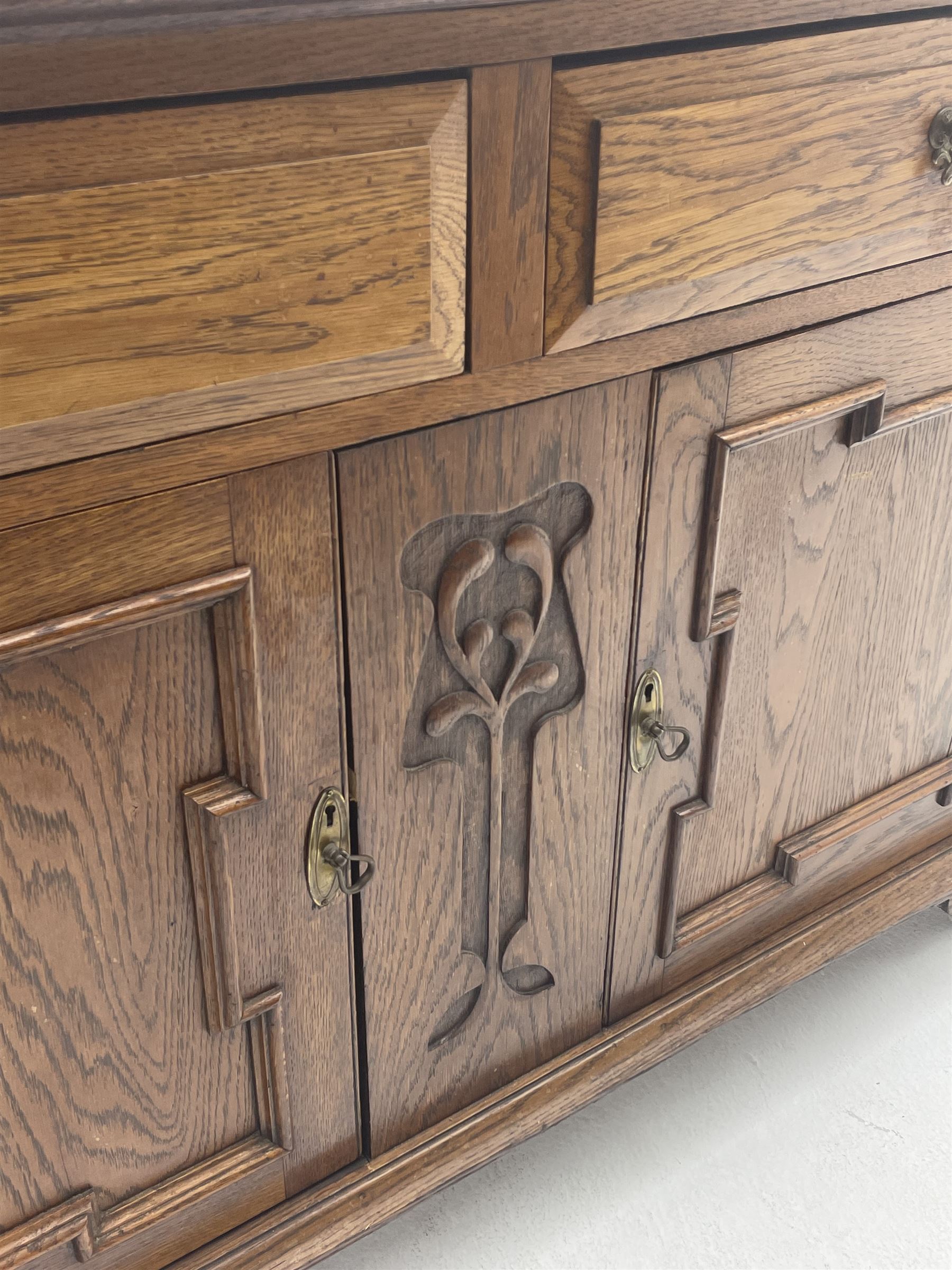Edwardian oak sideboard, raised and shaped back, two short drawers above two cupboard doors enclosing fitted interior, shaped bracket supports