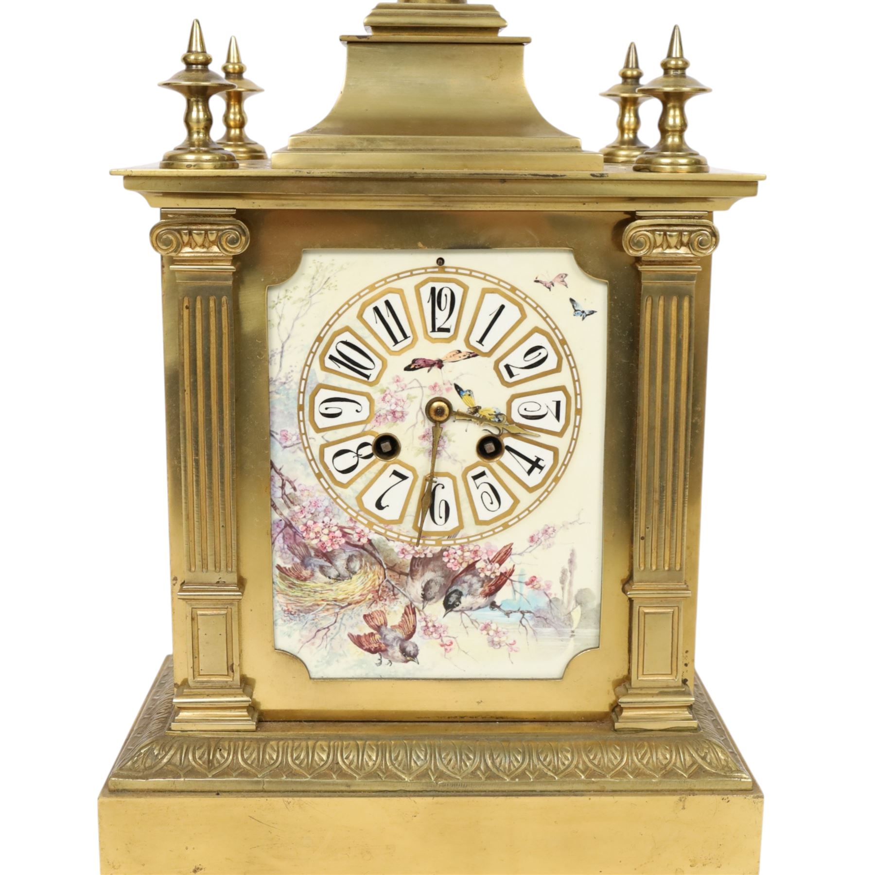 French gilt-bronze and porcelain mantel clock, architectural case surmounted by a stepped pediment with central urn finial and four subsidiary finials above two fluted Corinthian-style pilasters, the entire front inset with shaped porcelain panel incorporating a circular dial and numerals decorated with birds among flowering branches and two winding apertures and pierced brass hands, above a leaf and scroll cast frieze, raised on bracket feet, with an eight-day movement stamped 'AD MOUGIN Deux Medailles' striking the hours and half-hours on a coiled gong, with pendulum, circa 1900