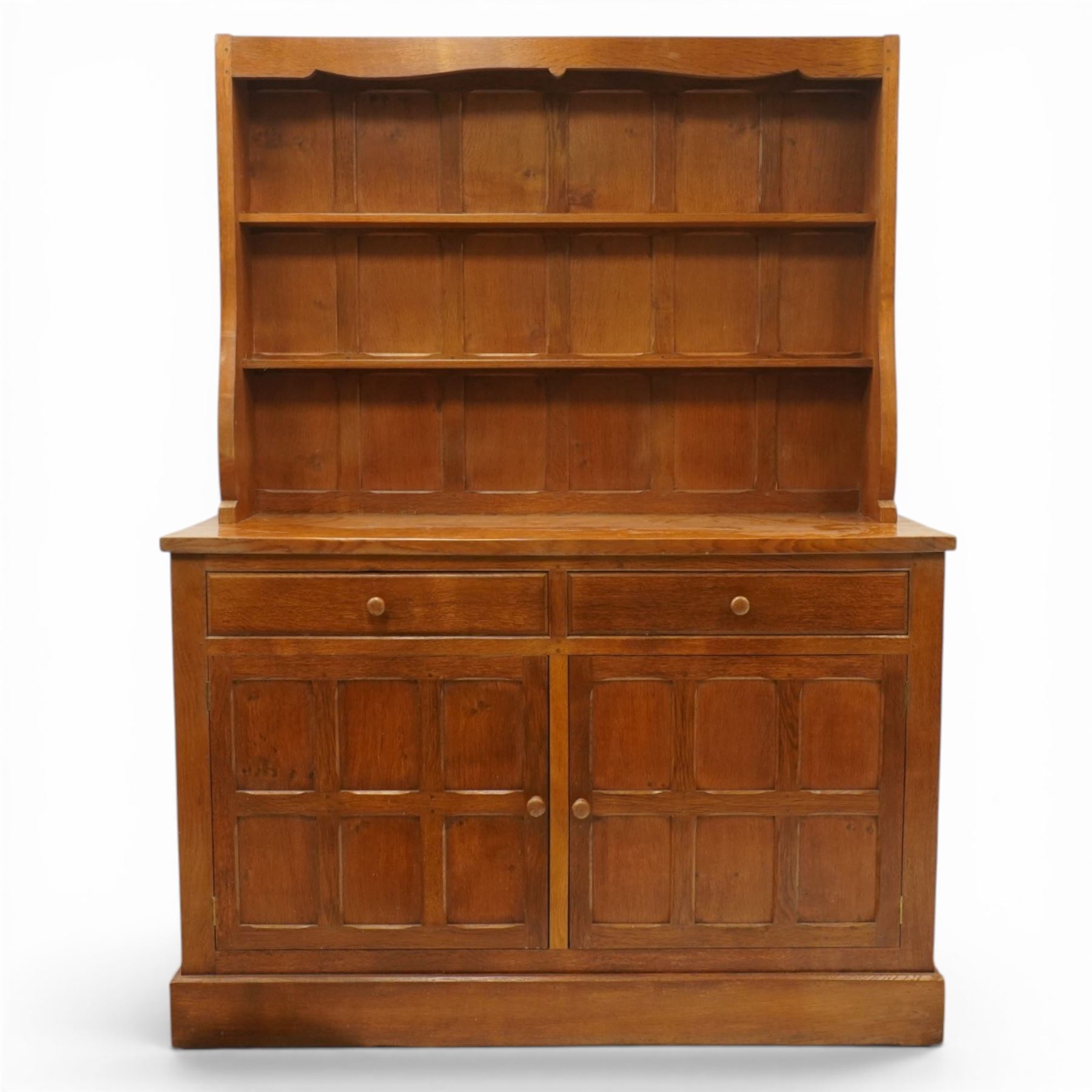 Cat and Mouseman - adzed oak dresser and plate rack, plate rack with two delf rack, panelled back and shaped uprights, above a base with two short drawers and turned wooden handles, panelled cupboard doors and sides, raised on a plinth base, with carved Cat and Mouseman signature, by Lyndon Hammell of Harmby