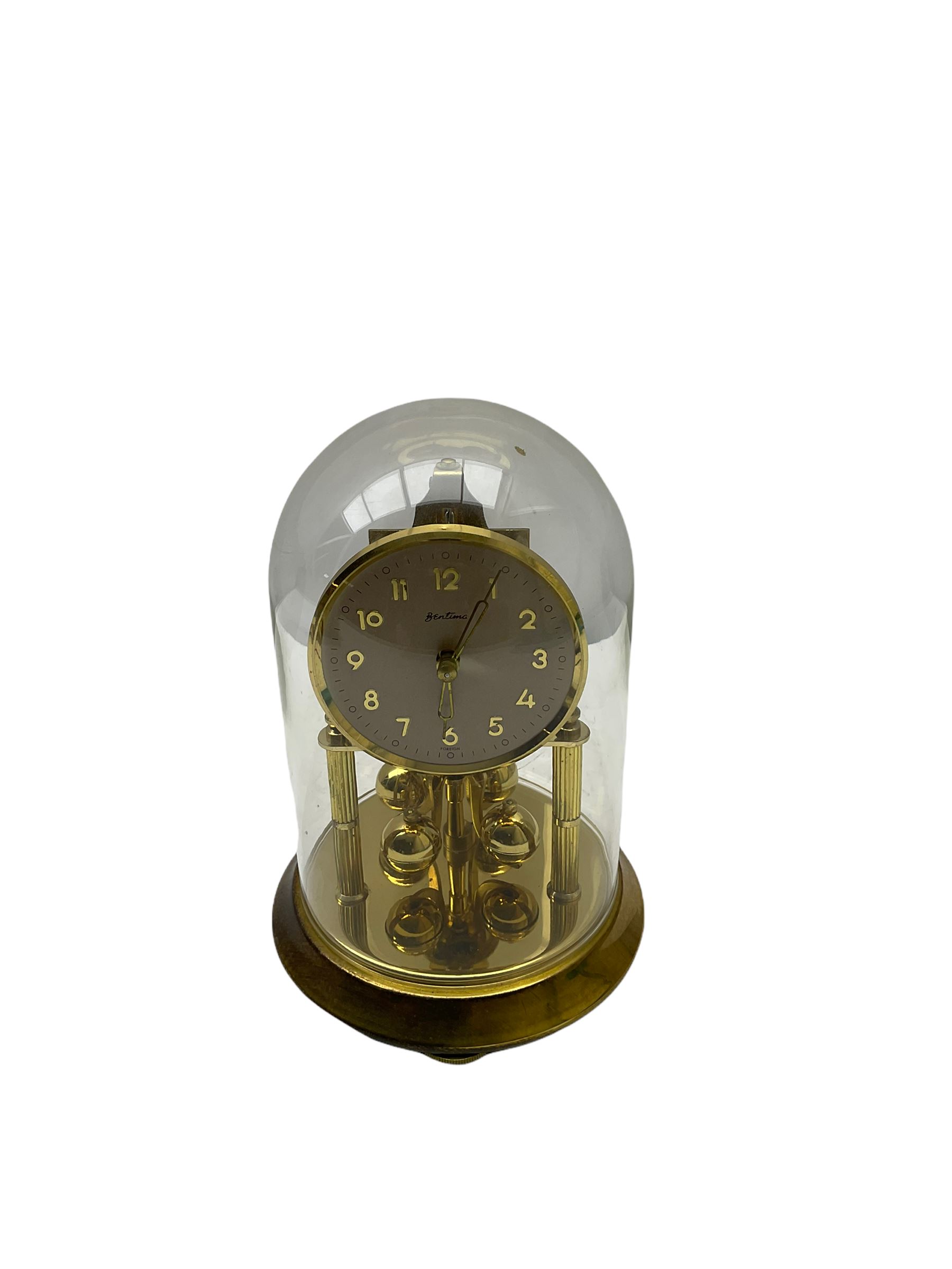 A 20th century English Torsion clock marketed by Bentime Ltd, London, with a four-ball rotary pendulum, white dial with gilt Arabic numerals and pierced gilt hands, under a glass dome, base with adjustable feet. No key.
Bentime Ltd did not make clocks but marketed clocks made by other companies such as J D Francis and Perivale.
H17
With a German Kundo torsion clock in a glazed rectangular case with four glass sides, four-ball rotary pendulum, white painted dial with gilt three-hour Arabic numerals and batons, with pierced brass hands. No key.
H15 W11 D9
