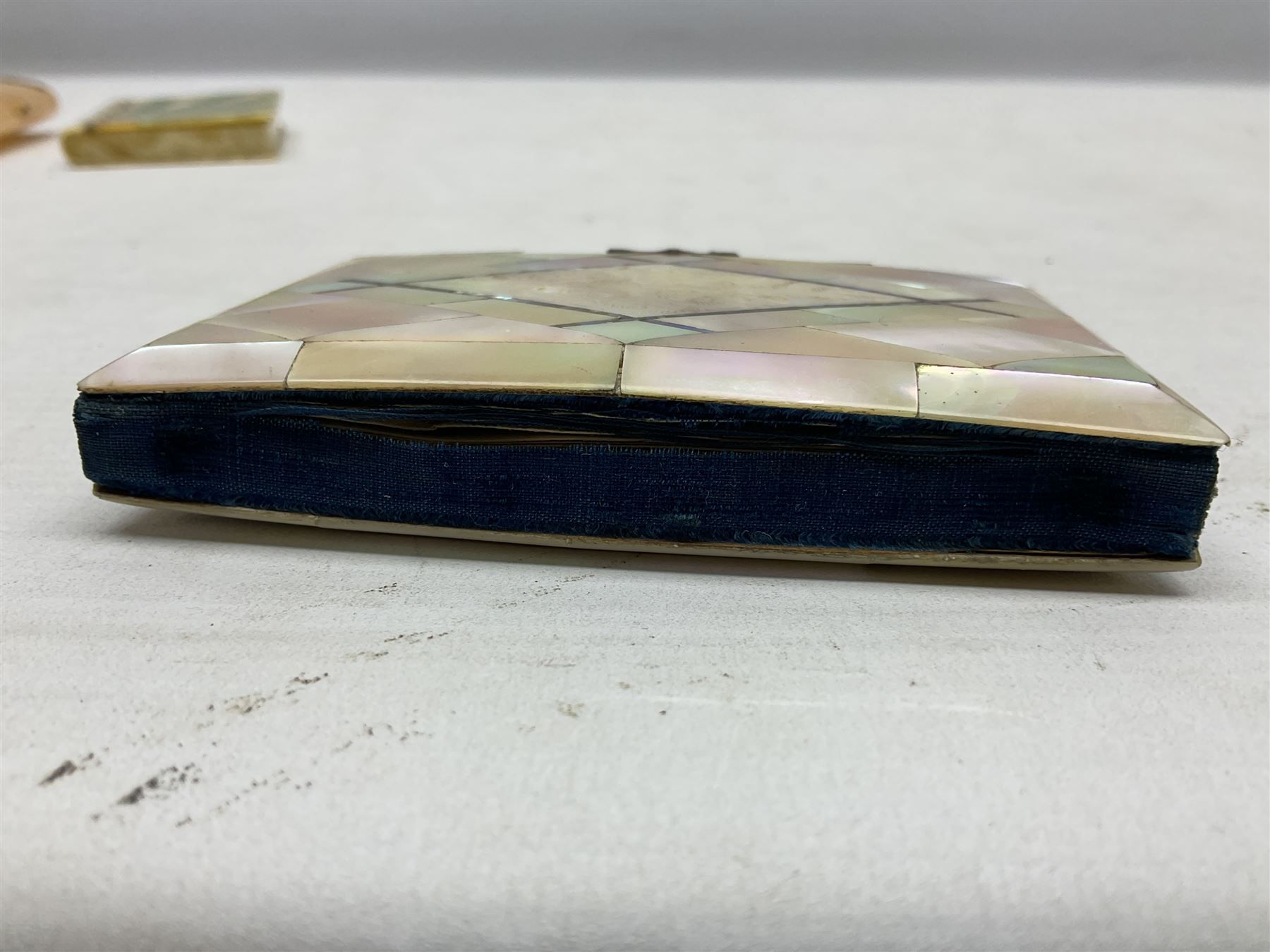 Mother of pearl and abalone inlaid card case, with central diamond shaped panel engraved with foliate decoration, together with a simulated mother of pearl card case of book form with green sun rays to cover, and simulated wood effect cigarette case with hinged lid with diamante style banding, largest L10cm