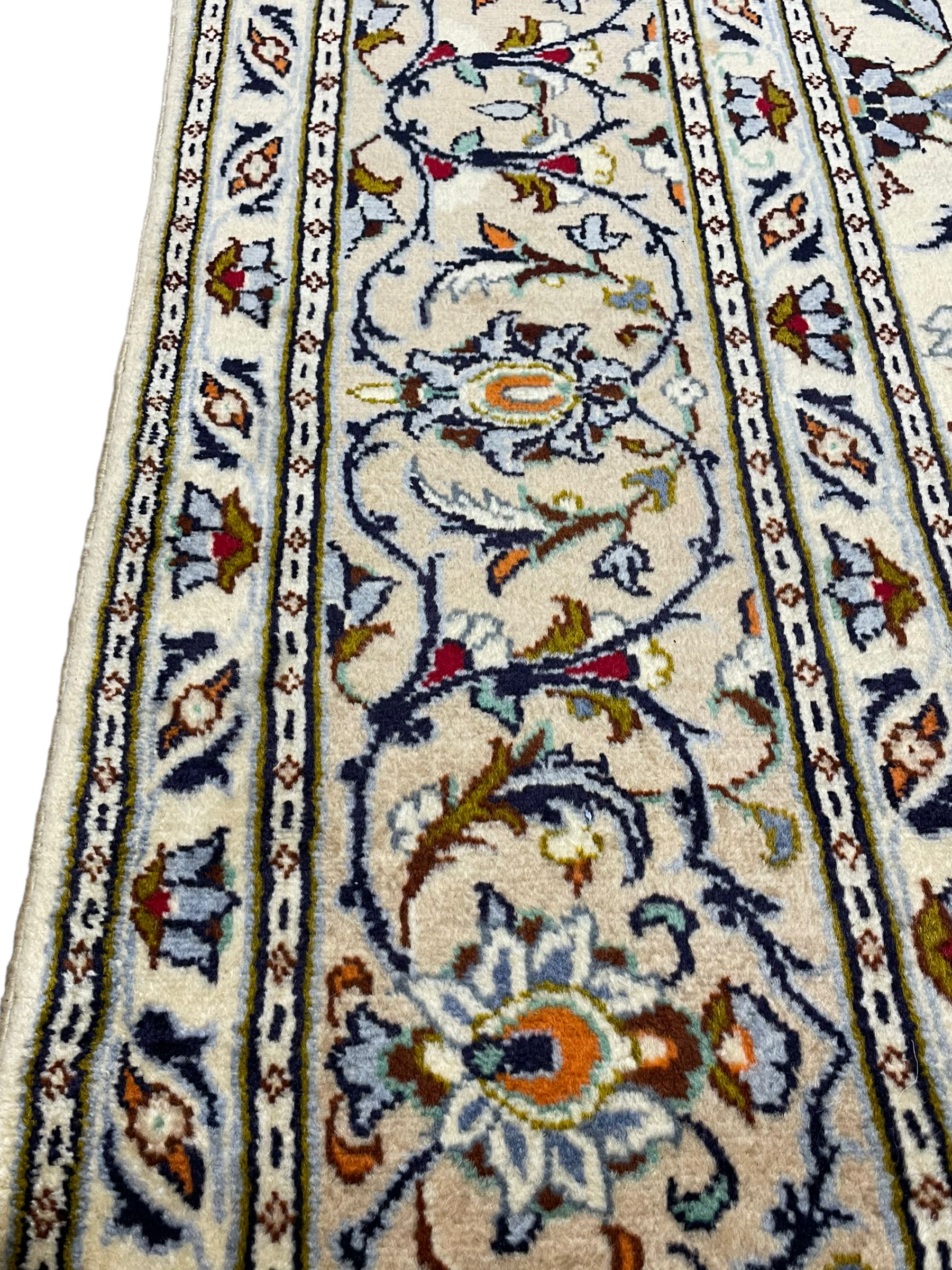 Persian Kashan ivory ground carpet, decorated all-over with interlacing foliate and stylised plant motifs, central scrolling medallion and matching spandrels, the guarded border decorated with repeating palmettes