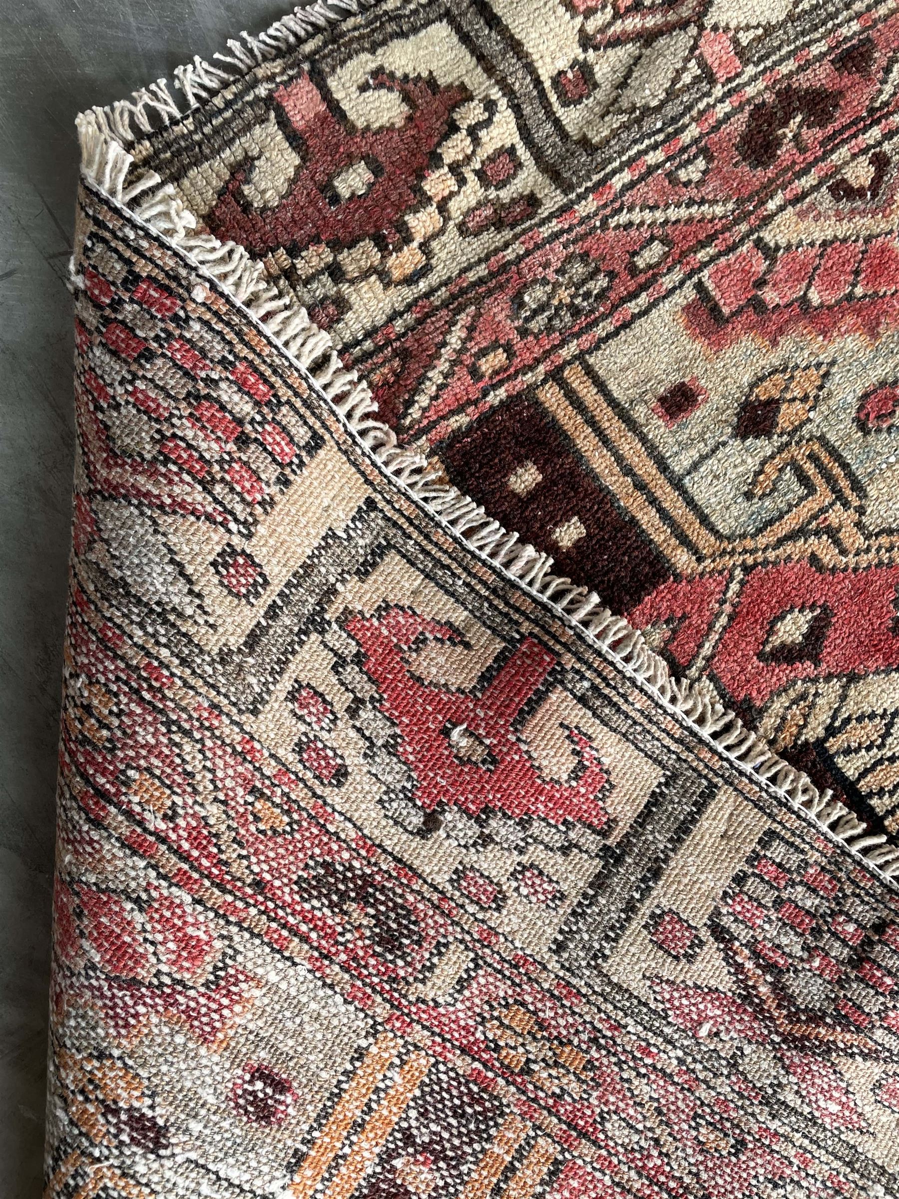 Persian Heriz red and pale ground rug, depicting multiple shaped panels with stylised motifs and designs, geometric patterned border