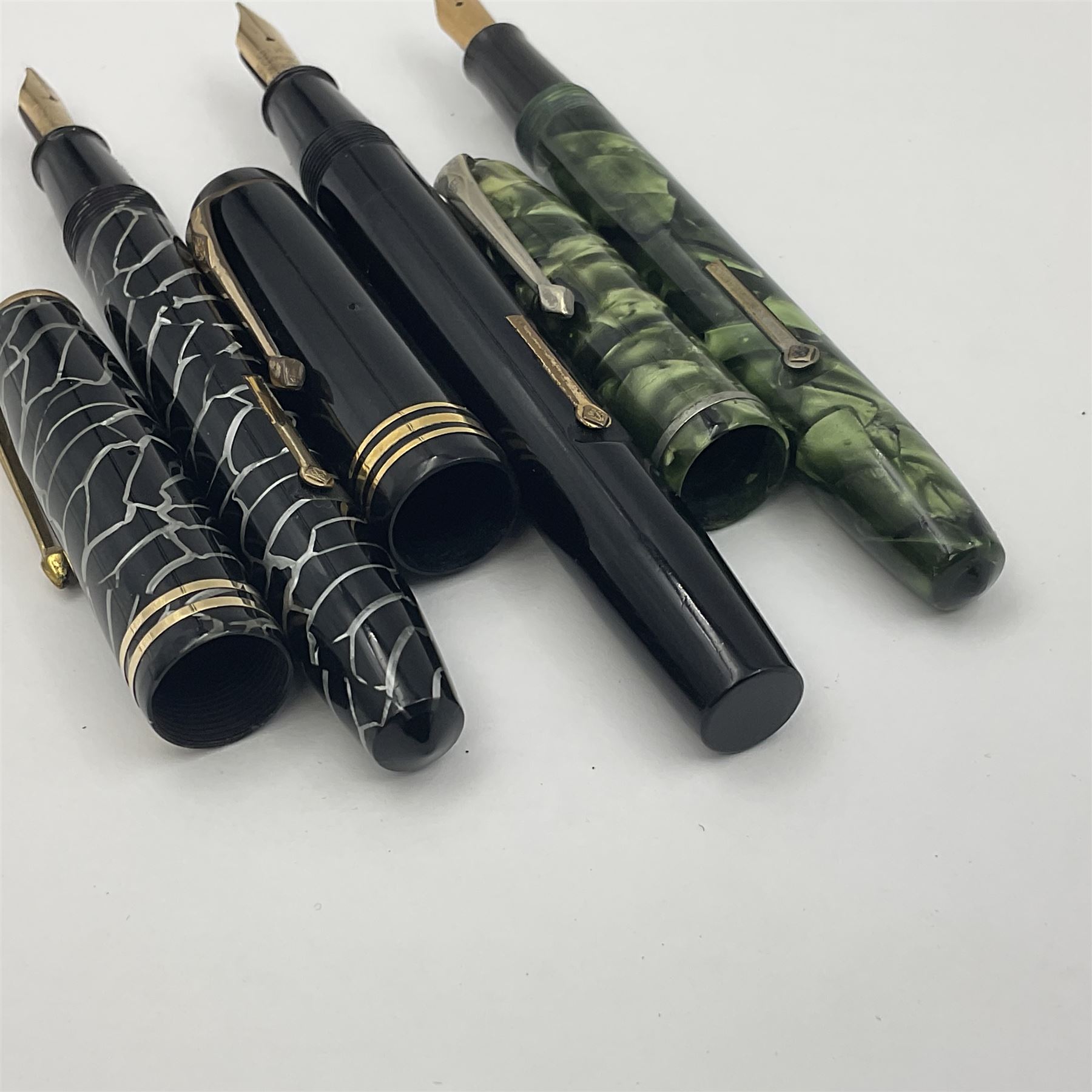 Three Conway Stewart fountain pens, comprising Cracked Ice 28 pen, the black and pearl white barrel engraved Conway Stewart 28 and double banded cap, with gold nib stamped 14ct, together with a Conway Stewart 75 lever fill pen, the green marble barrel and cap with single band and gold nib stamped 14ct and Conway Stewart 55 lever fill fountain pen with black barrel and cap with single broad band and two narrow bands with gold nib stamped Duro 14ct, largest L13cm