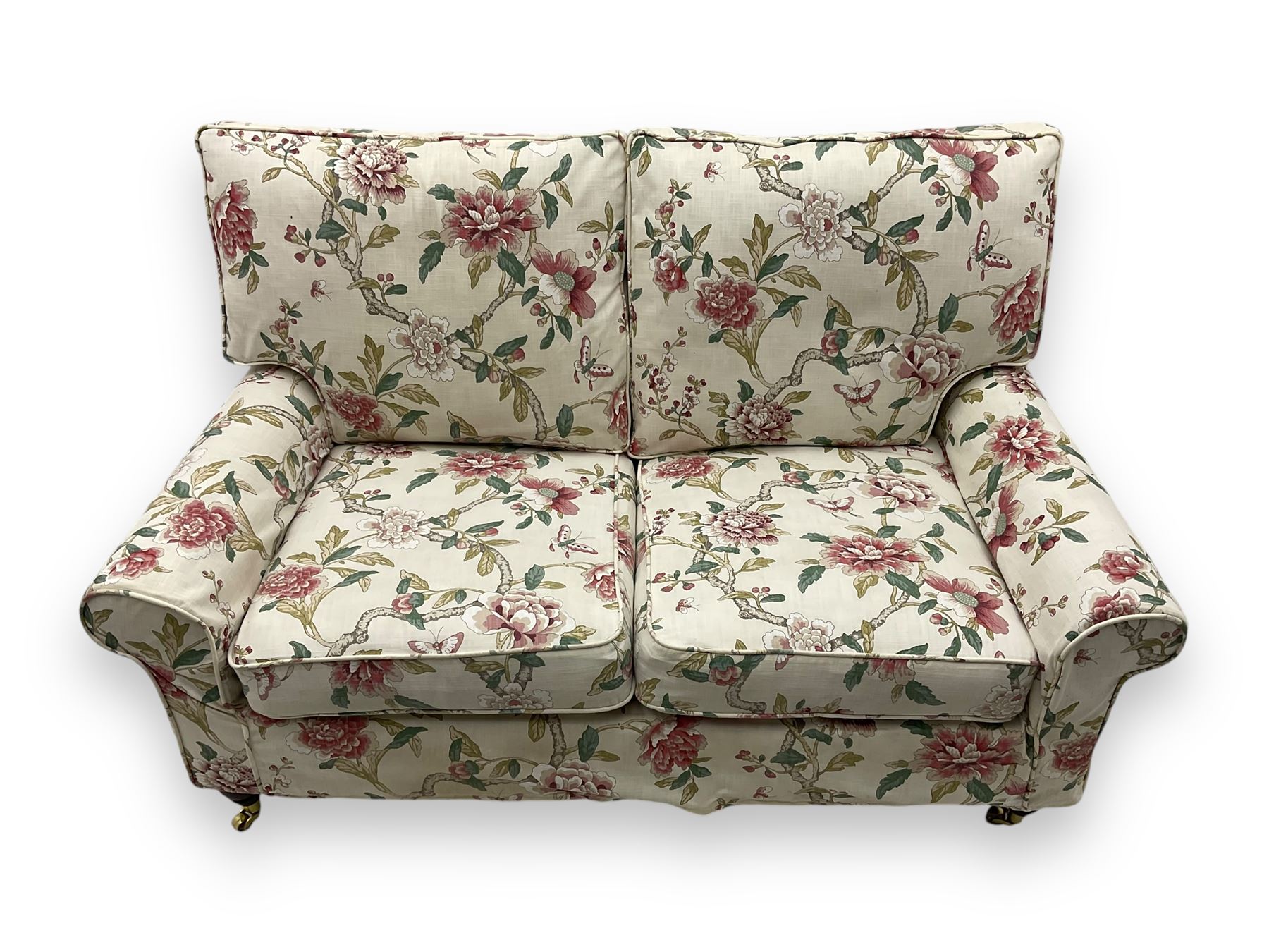 Steed Upholstery - 'Knightsbridge' two seater sofa, upholstered in cream fabric with pink and green floral design, loose back and seat cushions, raised on mahogany supports with brass castors