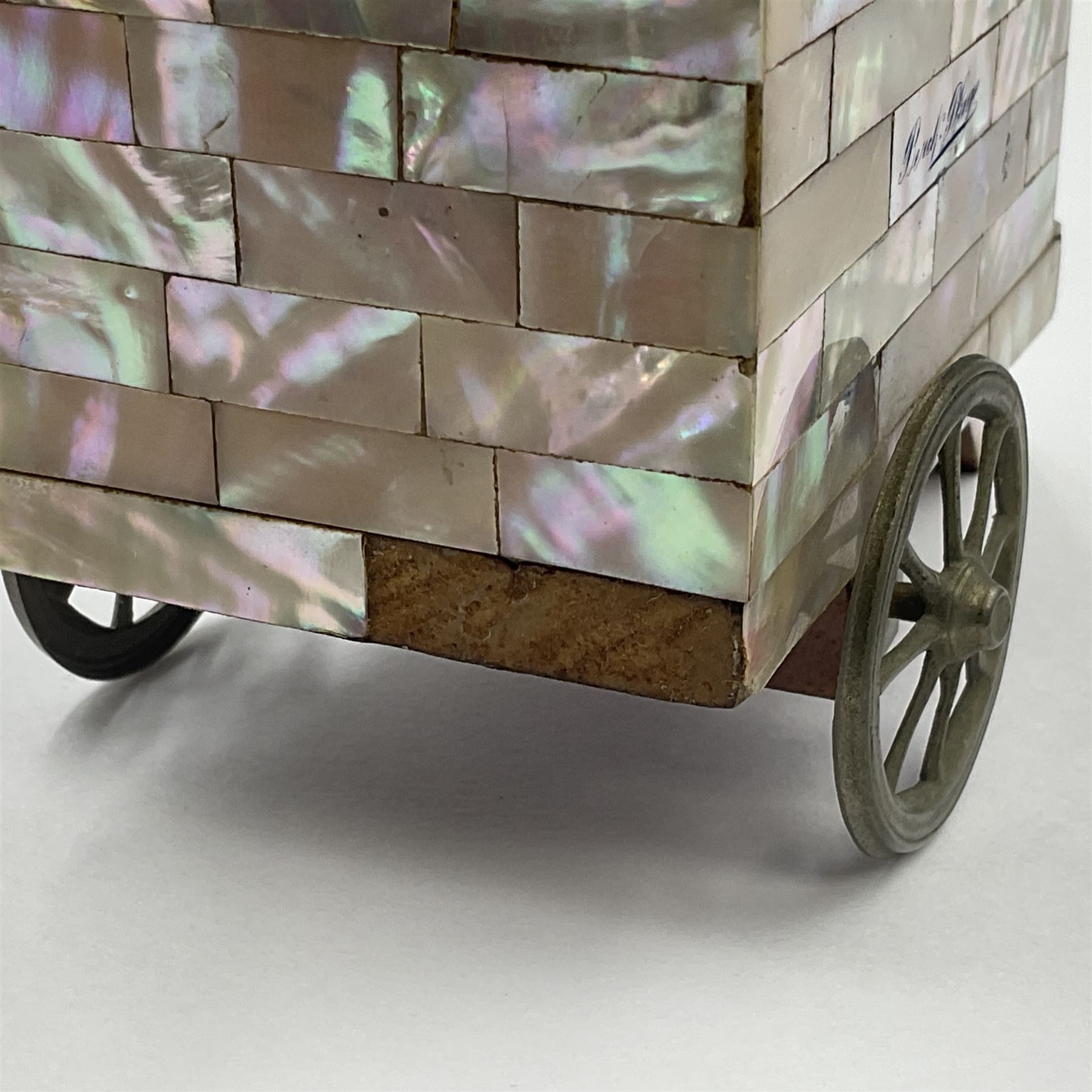 19th century French souvenir jewellery casket in the form of a bathing machine, having mother of pearl panelled tiled effect body, hinged roof/cover revealing a blue silk fitted interior with cushioned base, two silvered metal wheels, abalone shell door and mother of pearl steps, inscribed 'Berck Plage' in blue, H12cm, W13cm 