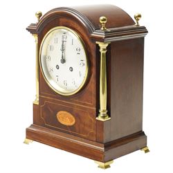 Edwardian-French mahogany cased mantle clock c1910 in a break-arch case with brass finials and recessed brass columns, with inlaid satinwood stringing and conche inlay to the front, raised on a short plinth with bracket feet, twin train movement with rack striking, sounding the hours and half-hours on a coiled gong.
With pendulum and key.