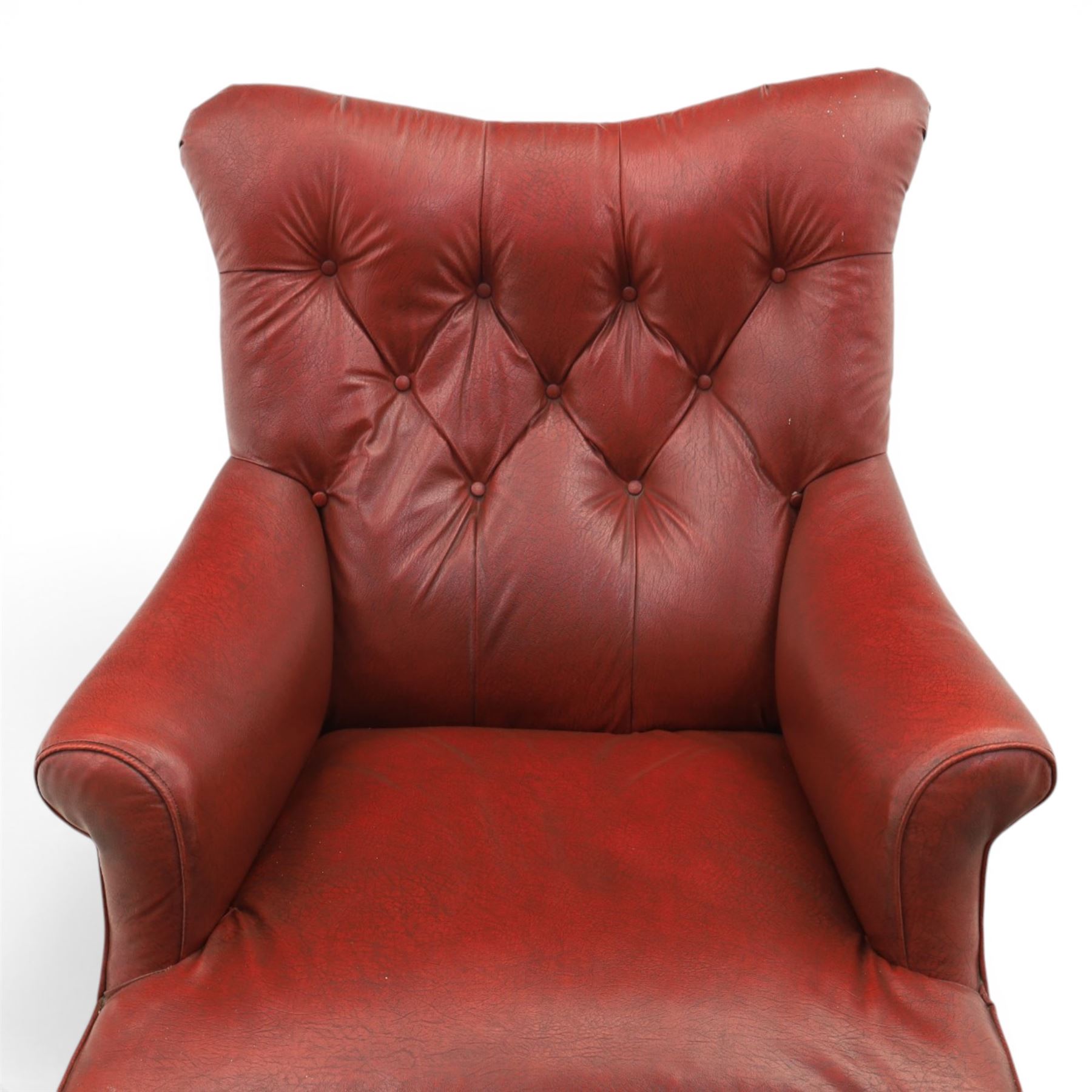 Early 20th century style oxblood red leather Chesterfield armchair, deep buttoned shaped back over padded scroll arms and loose seat cushion, raised on turned mahogany front supports with brass caps and castors