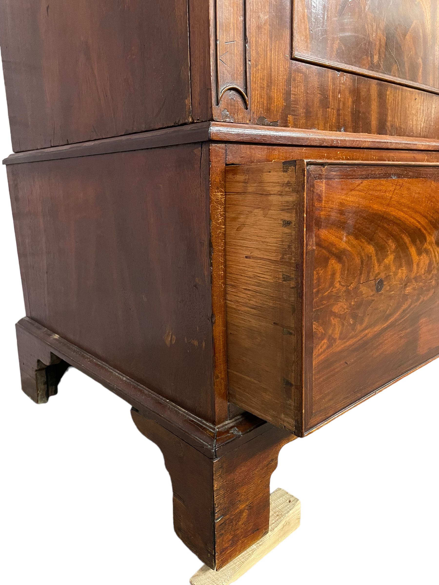 George III mahogany double wardrobe, the projecting cornice with dentil moulding over two panelled doors with mirror-lined interiors, enclosing hanging rails and brass hooks, the base fitted with two drawers, raised on bracket feet