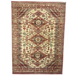  Persian design red ground rug, the field decorated with three interlinked lozenges and small stylised plant motifs, the multiple band border decorated with Boteh and floral motifs