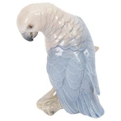 Two Royal Copenhagen figurines of fawns, comprising a fawn with an owl, no 2107 and fawn on plinth no 433, together with Bing & Grondahl, figure of a parrot on branch