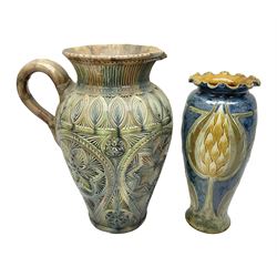  Early 20th century Royal Doulton stoneware vase, decorated with a stylized floral design below a wavy rim, monogrammed B.N, possibly for Bessie Newbery, H28cm, together with an early 20th century glazed jug, heavily carved throughout (2)