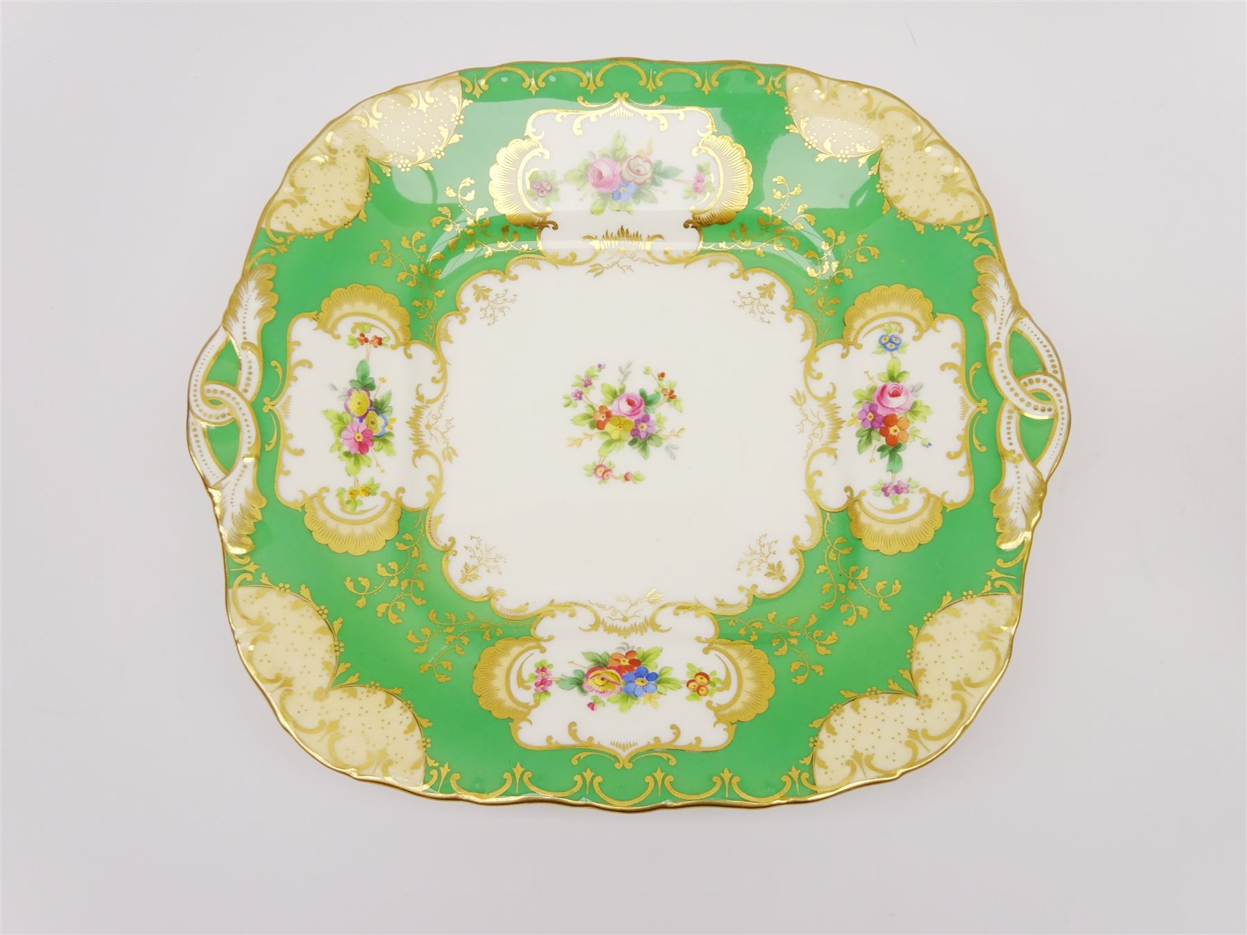 19th century Minton tea set, comprising twelve teacups, eleven saucers, fifteen side plates, cream jug, slop bowl, and two cake plates, decorated with panels of floral sprays, upon a green ground, heightened with gilt throughout, with printed puce mark beneath, and pattern number 5329
