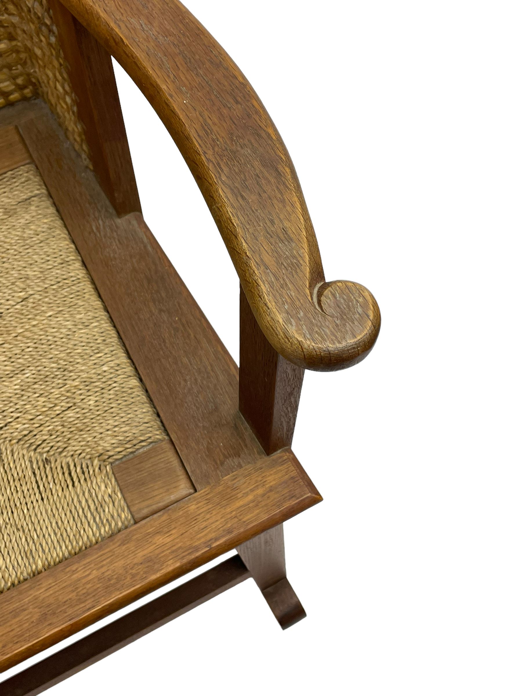 Reynold Eunson (1932–1978) for David Munro Kirkness, Kirkwall, Orkney - oak framed Orkney rocking chair, woven straw curved back, drop-in rush seat, the arm terminals with carved end scroll, on square tapering supports joined by plain stretchers, the front rail inscribed with makers marks