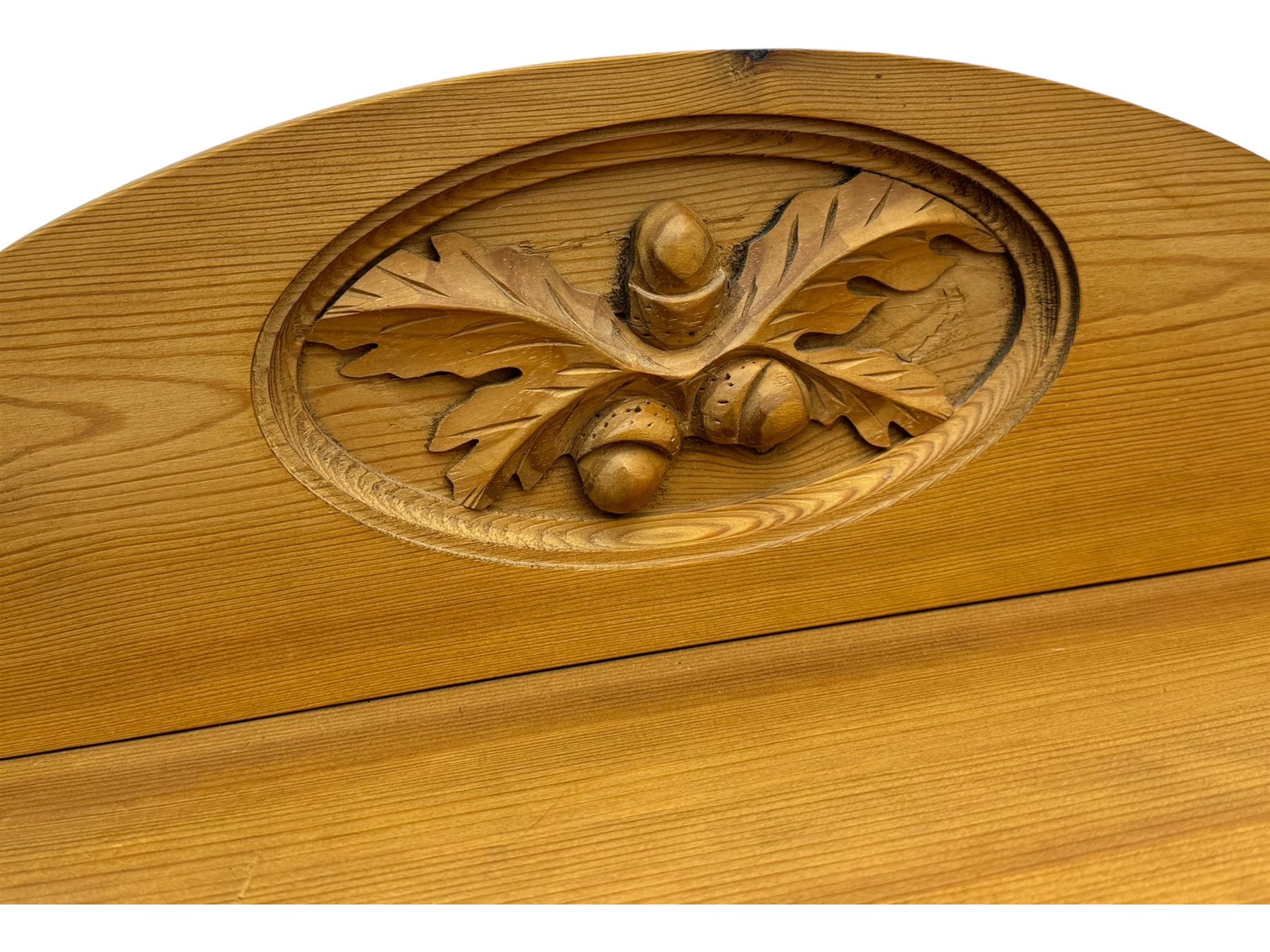 Pine chest of drawers topped with carved pediment with acorn and oak leaf motif, fitted with two short over three long drawers, standing on shaped apron base (W92, D46, H97cm); pine bedside cabinet, single drawer above paneled cupboard door enclosing open storage, shaped plinth base (W43, L32, H67cm)