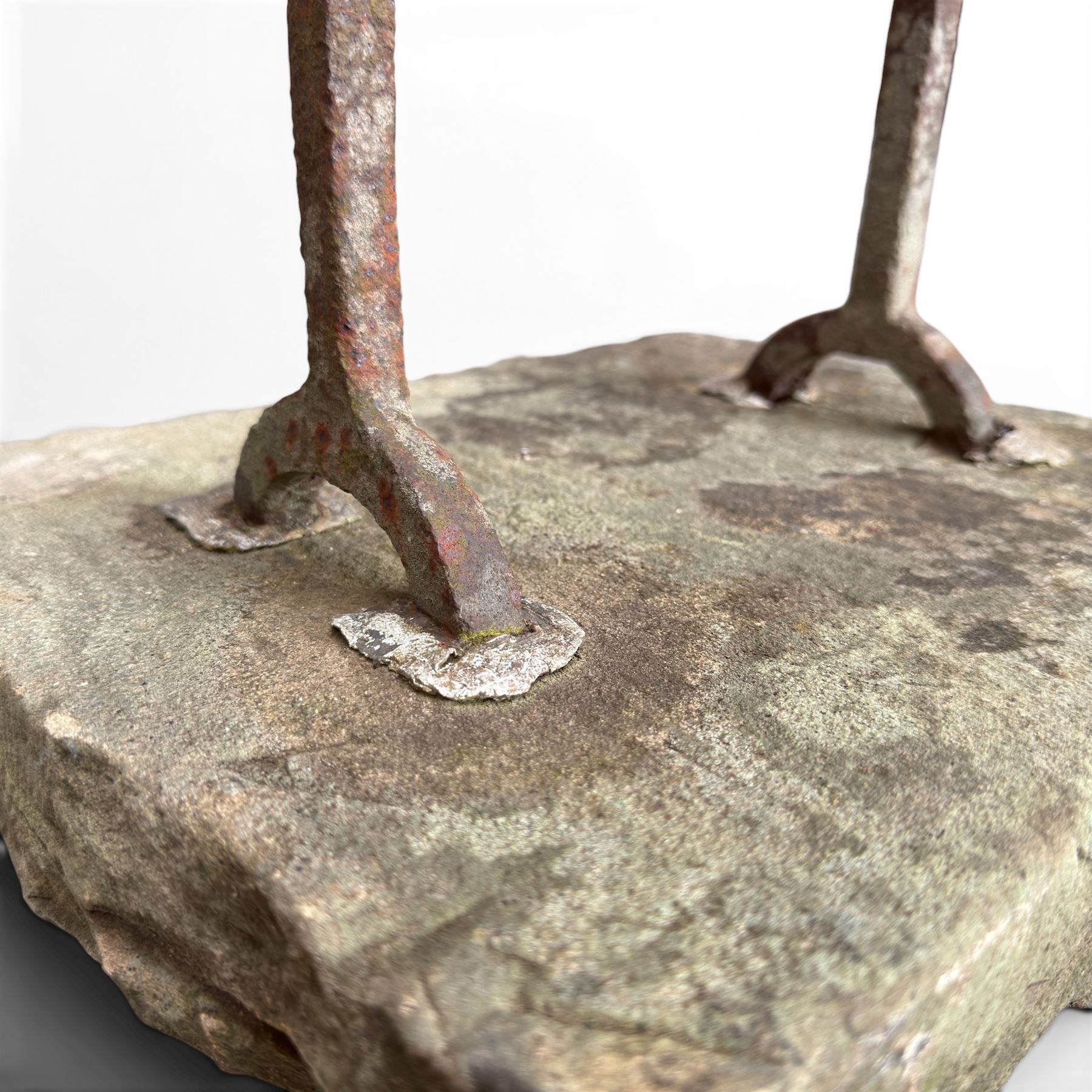 19th century cast iron boot scraper, mounted on a rectangular hewn stone slab base, with scrolled twin upright supports and scraper bar, in weathered finish