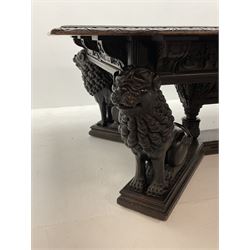 Large 19th century carved oak library table, the rectangular top with lunette carved edge over cartouche panelled and carved  scroll frieze, the central tapering rectangular support relief carved with masks and garlands, on four carved seated lion supports at each corner, on flat angular stretcher with recessed castors stamped ‘Bartholomew & Fletcher, London’