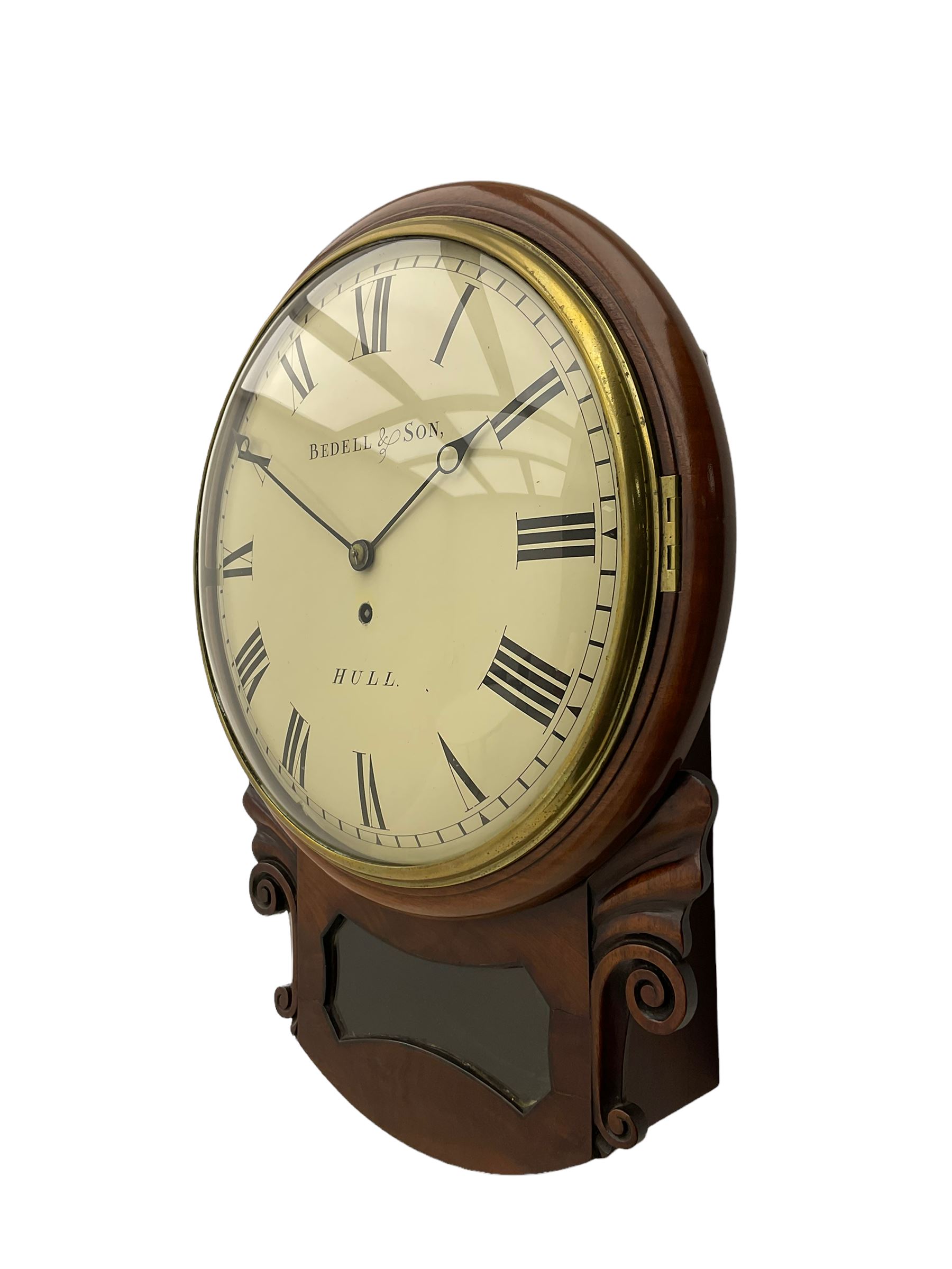 A single fusee 8-day drop dial mahogany cased wall clock, c1860 with a 14-1/2” wooden bezel and 12” painted convex dial, cast brass bezel and convex glass, dial with retailer's name “Bedell & Son, Hull”, Roman numerals, minute track and matching steel moon hands, with a recoil anchor escapement and rectangular movement plates, case with scroll carved ears and glazed pendulum aperture, pendulum location door and a pendulum regulation door to the curved base. With pendulum.
***Peter and Benjamin Bedell were a family of 19th century Hull clockmakers working from various locations in Hull between 1823 and 1872.
