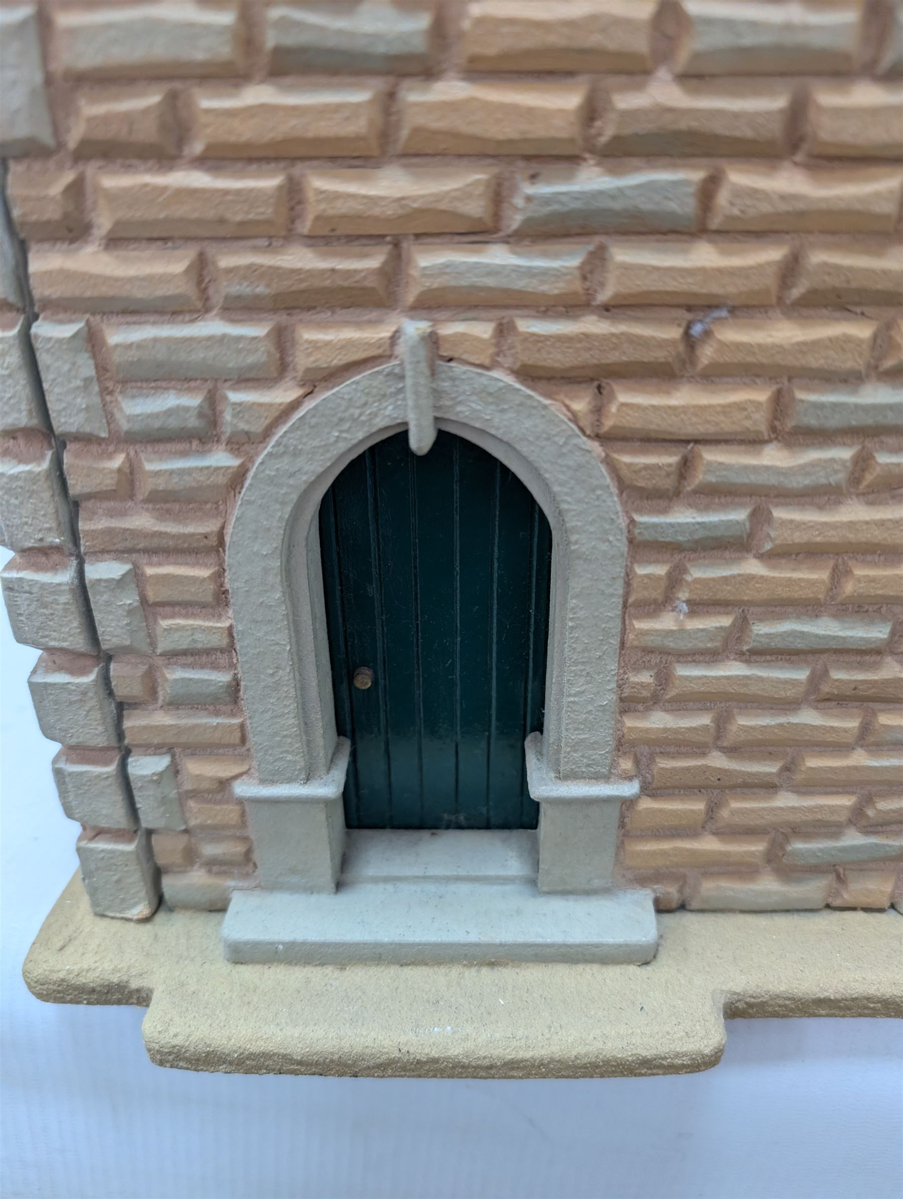 1:24 scale stone effect three-storey cottage dolls house, with green arched door and lattice effect windows, decorated to the interior with wooden floors, wired lighting and fire places, H45cm, W57cm, D26cm