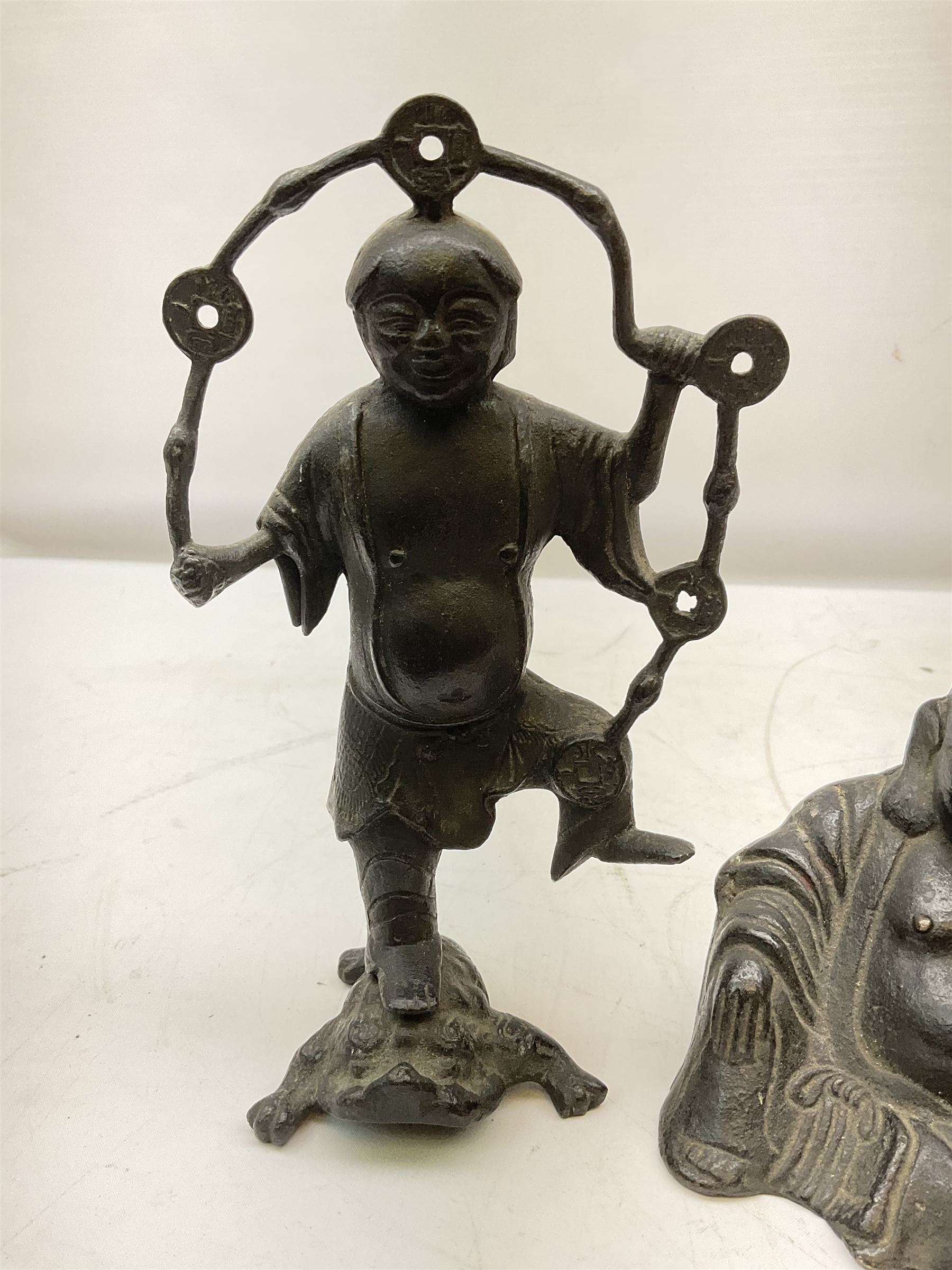 Cast iron figure of Liu Hai, the Chinese God of Wealth modelled standing with one foot upon mythical three-legged chánchú toad and holding a string of Chinese coins, H21cm, together with a cast iron figure of a seated laughing Buddha