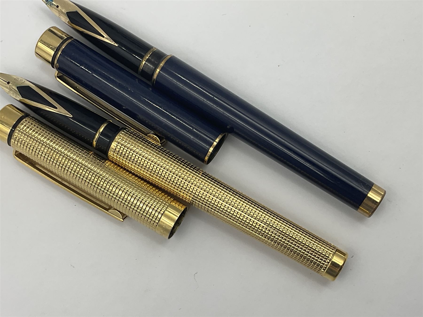 Sheaffer Targa 1011 Diamond Square fountain pen, the gold plated barrel with nib stamped 14K 585, together with another Sheaffer Targa fountain pen with blue barrel and gold nib stamped 14K 585 and matching ballpoint, and Sheaffer ballpoint pen with sterling silver barrel, largest L13.5cm (4)